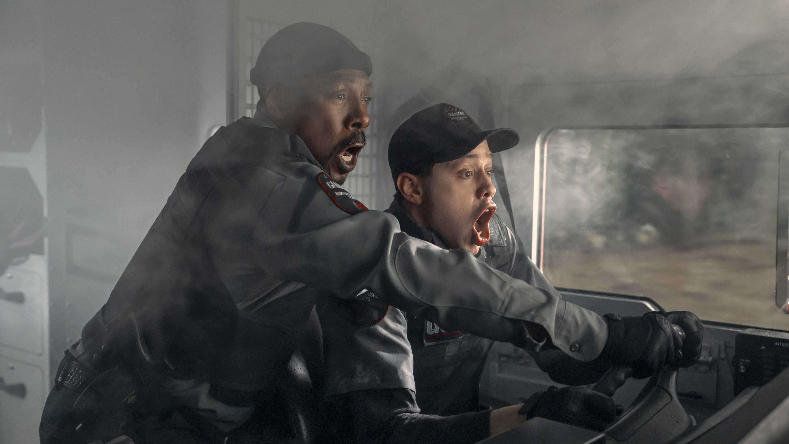 Two men in uniform shouting in alarm while operating a vehicle