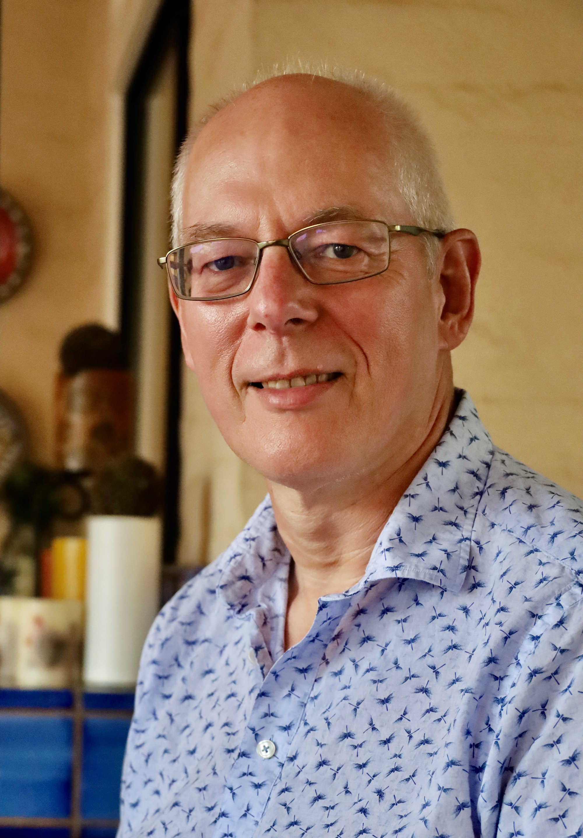 A white man with light, close-cropped hair and glasses smiles at the camera.