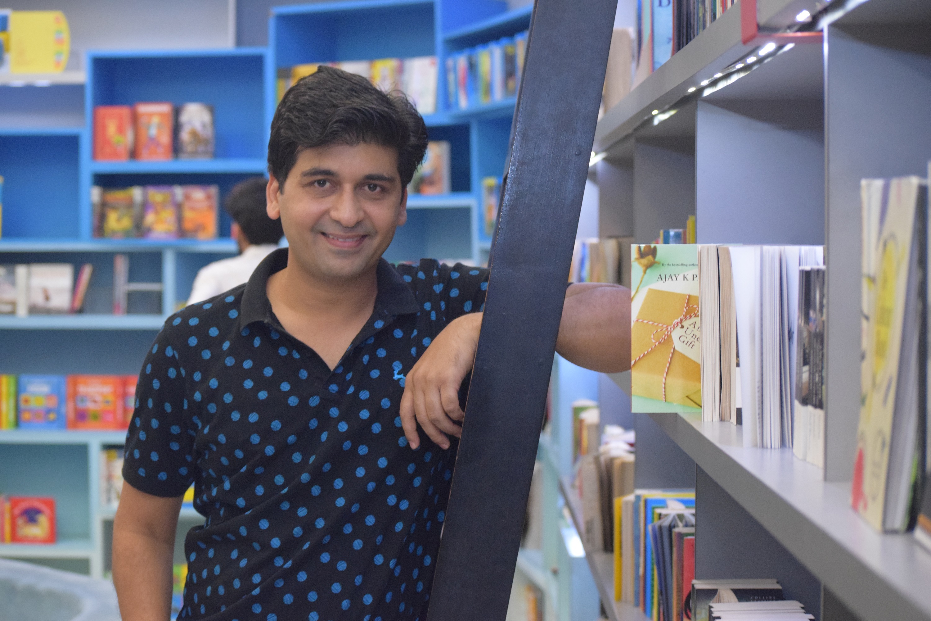 Ajay Pandey poses next to a book shelf