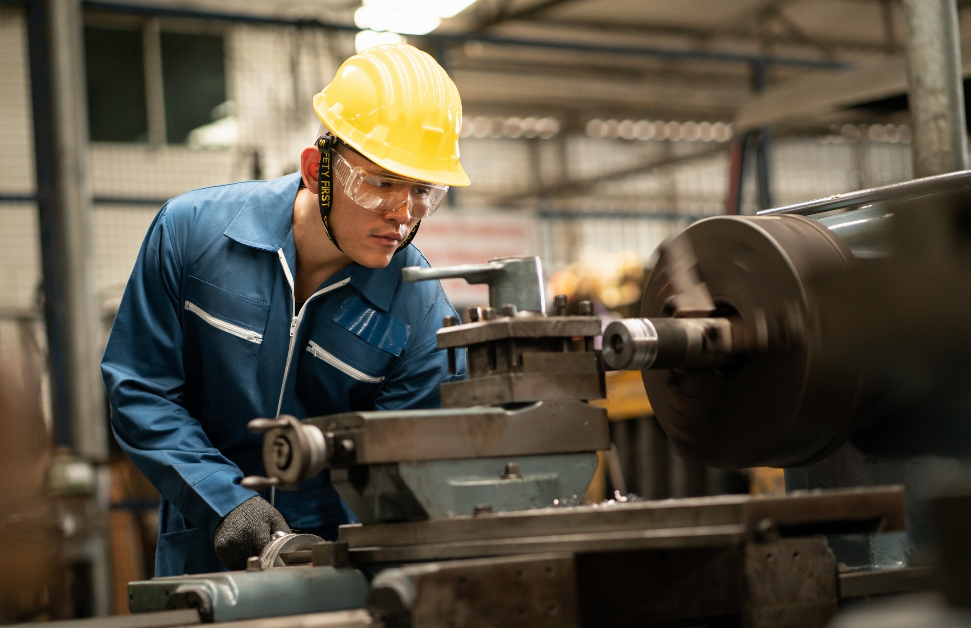 A man wears safety gear has he works with machinery.