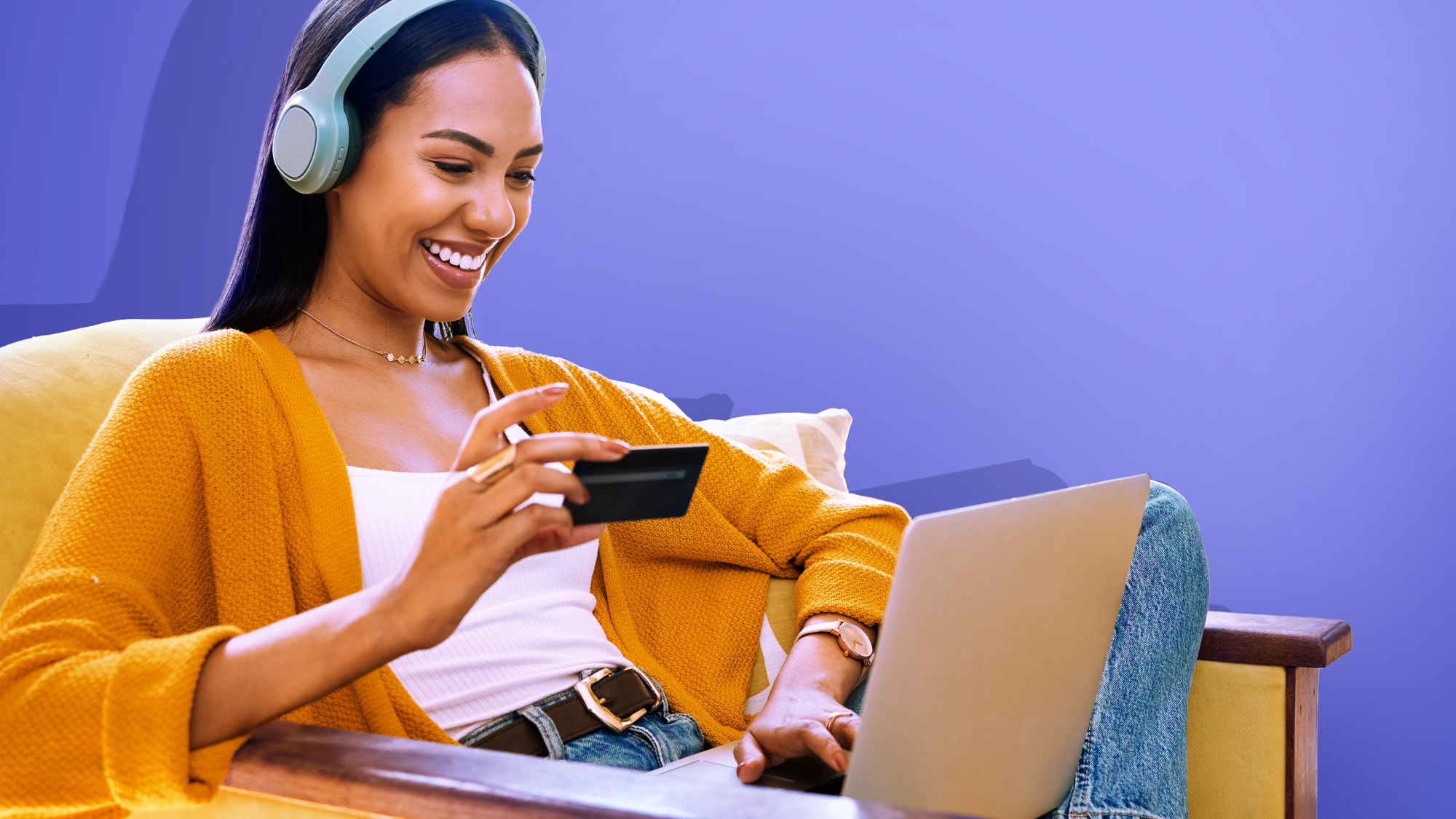 An image of a woman typing on her laptop with one hand and holding a credit card with the other on a purple background. 