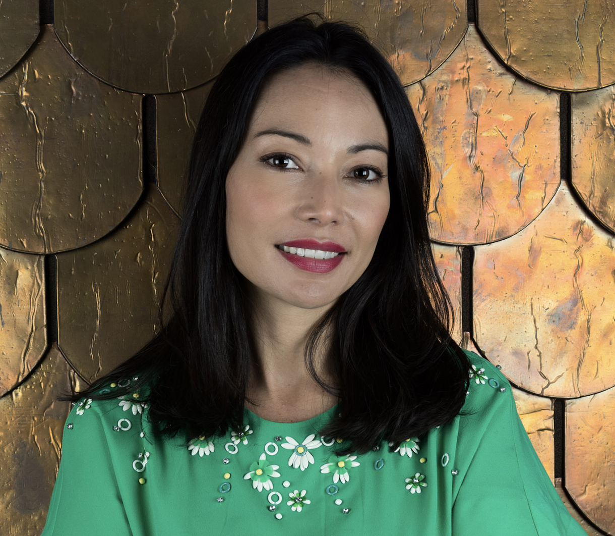 A woman smiles at the camera, her arms crossed in front of her. 