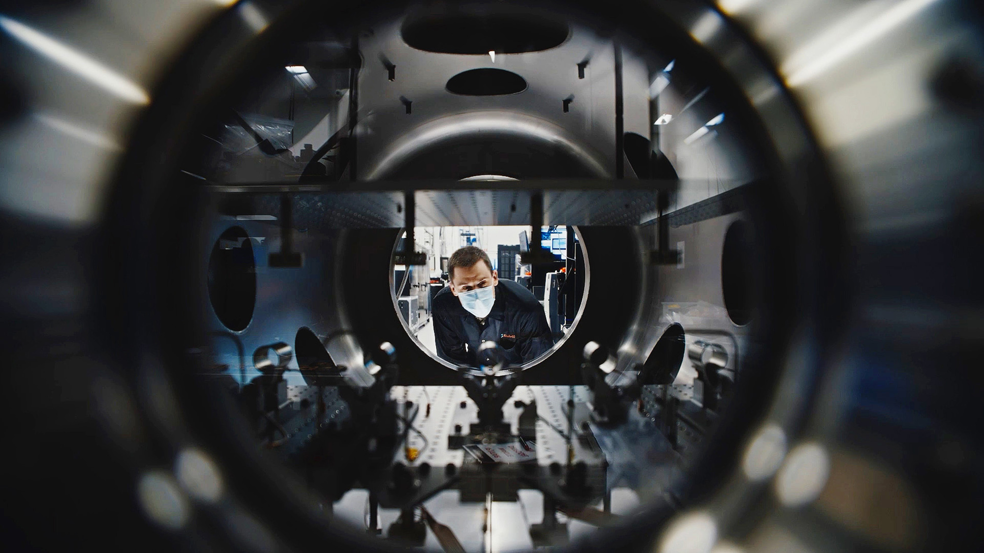 Masked technician inspects equipment at Amazon Leo manufacturing facility