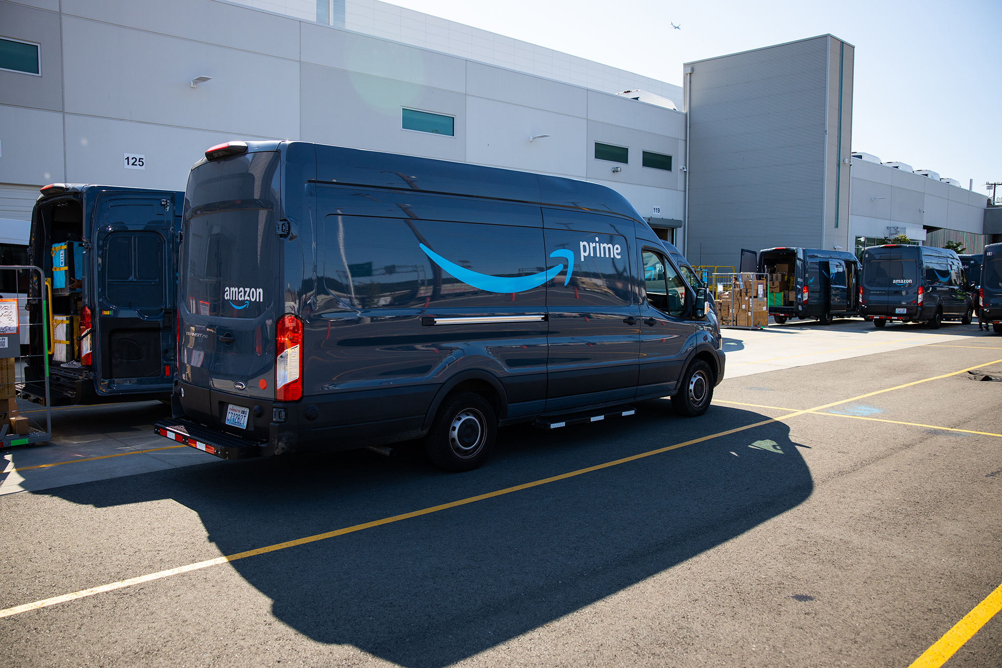 Amazon delivery vehicles are lined up outside a fulfillment center.