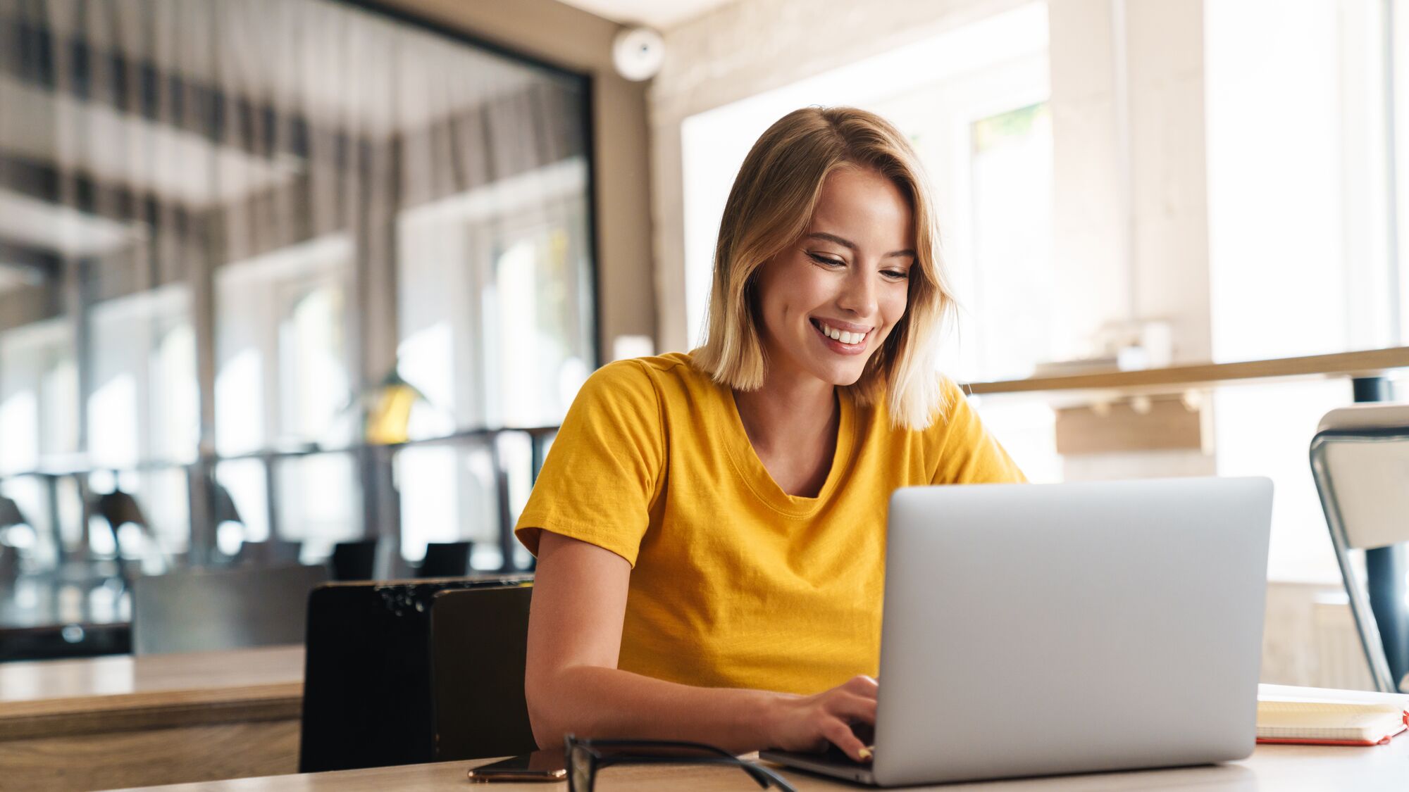 eine Frau lächelt, während sie an ihrem Laptop arbeitet