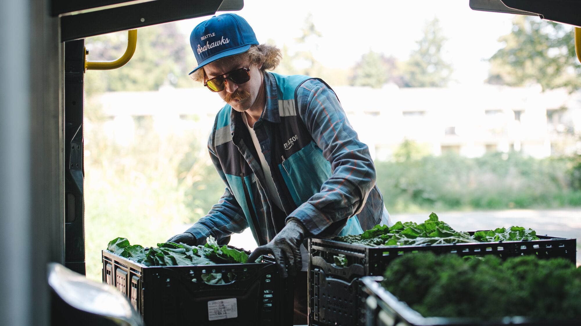 Delivery worker in blue cap loading crates of fresh produce
