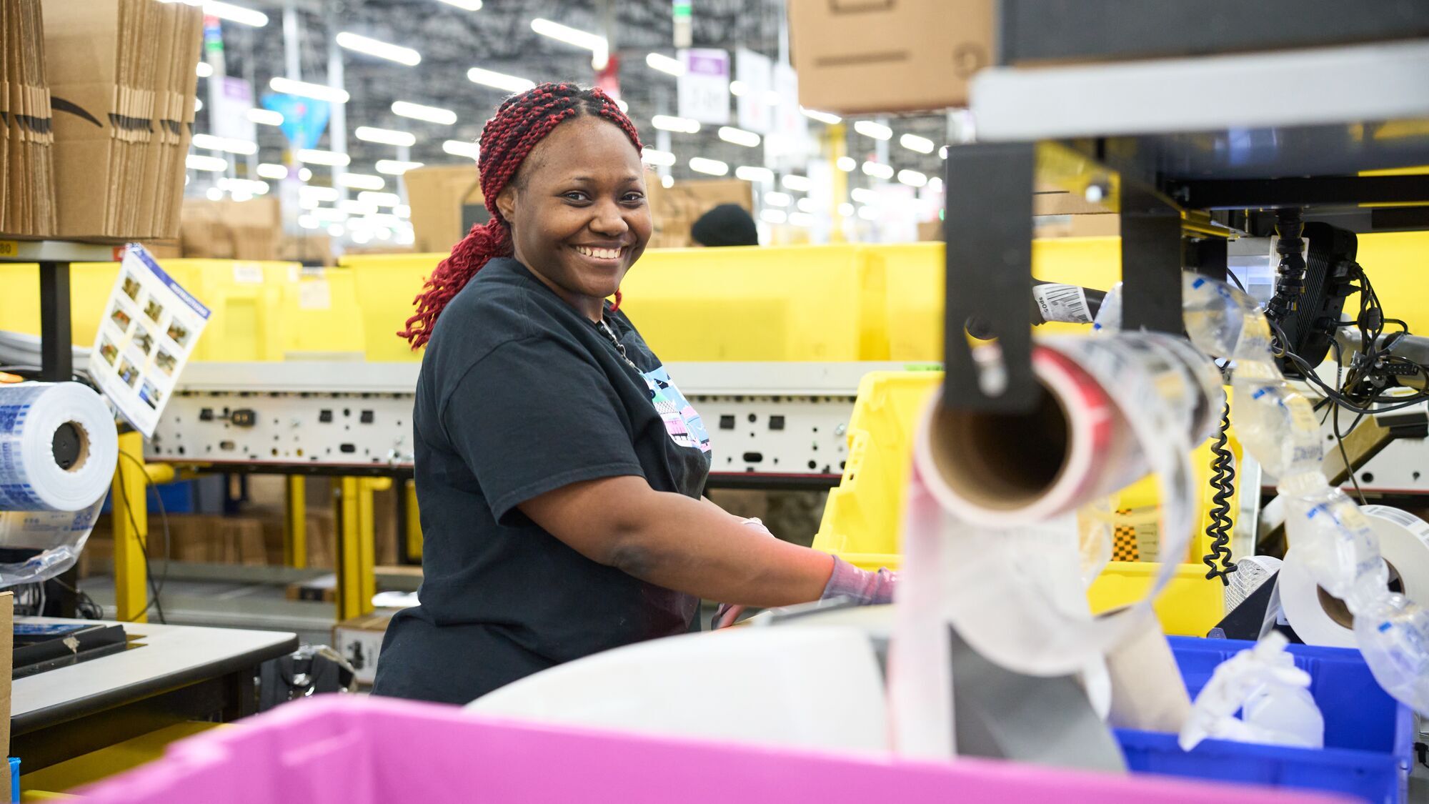 operations employee smiling at the camera as she completes orders at an Amazon fulfillment center