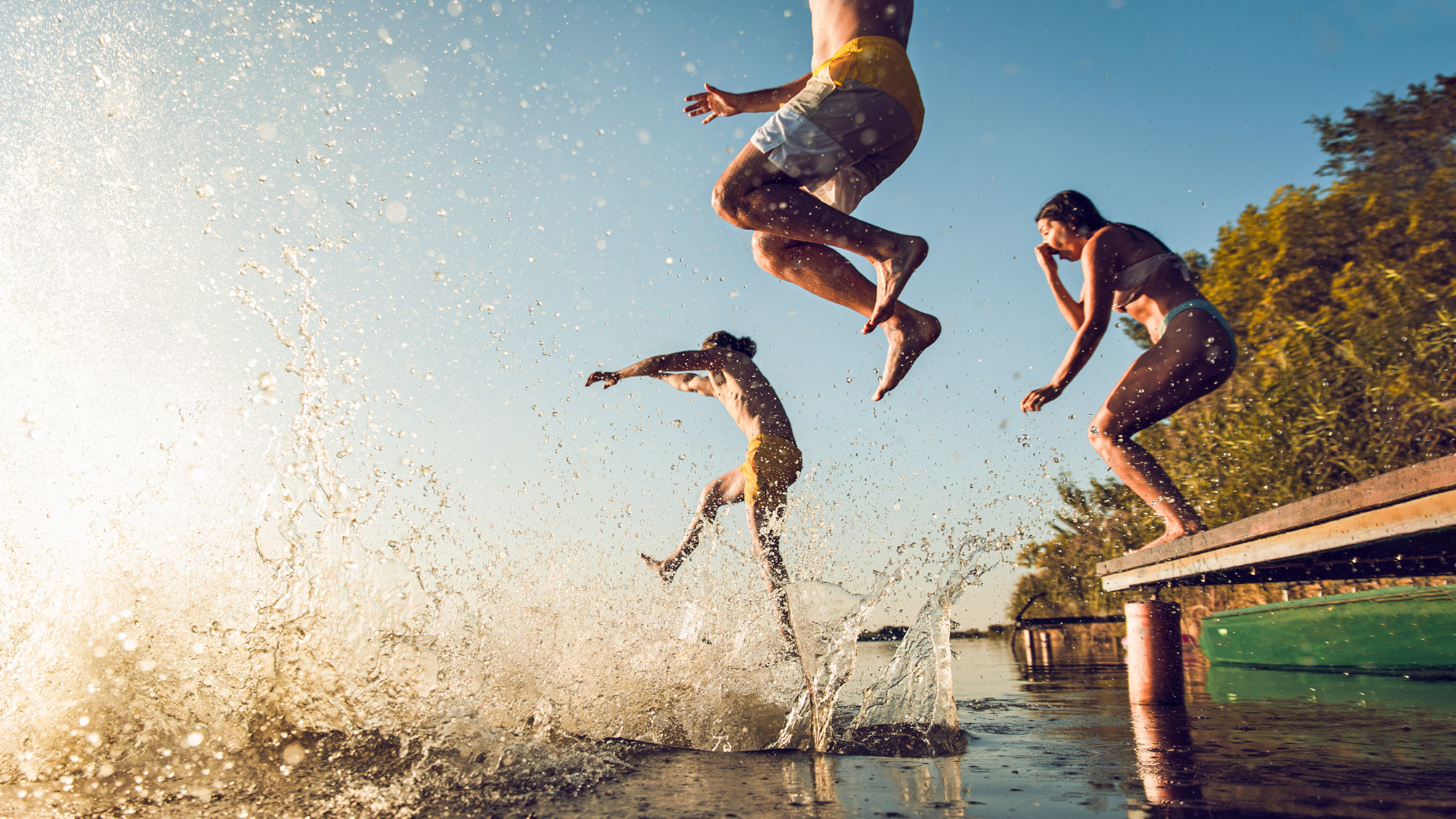 Junge Leute genießen den Sommer und springen in einen See