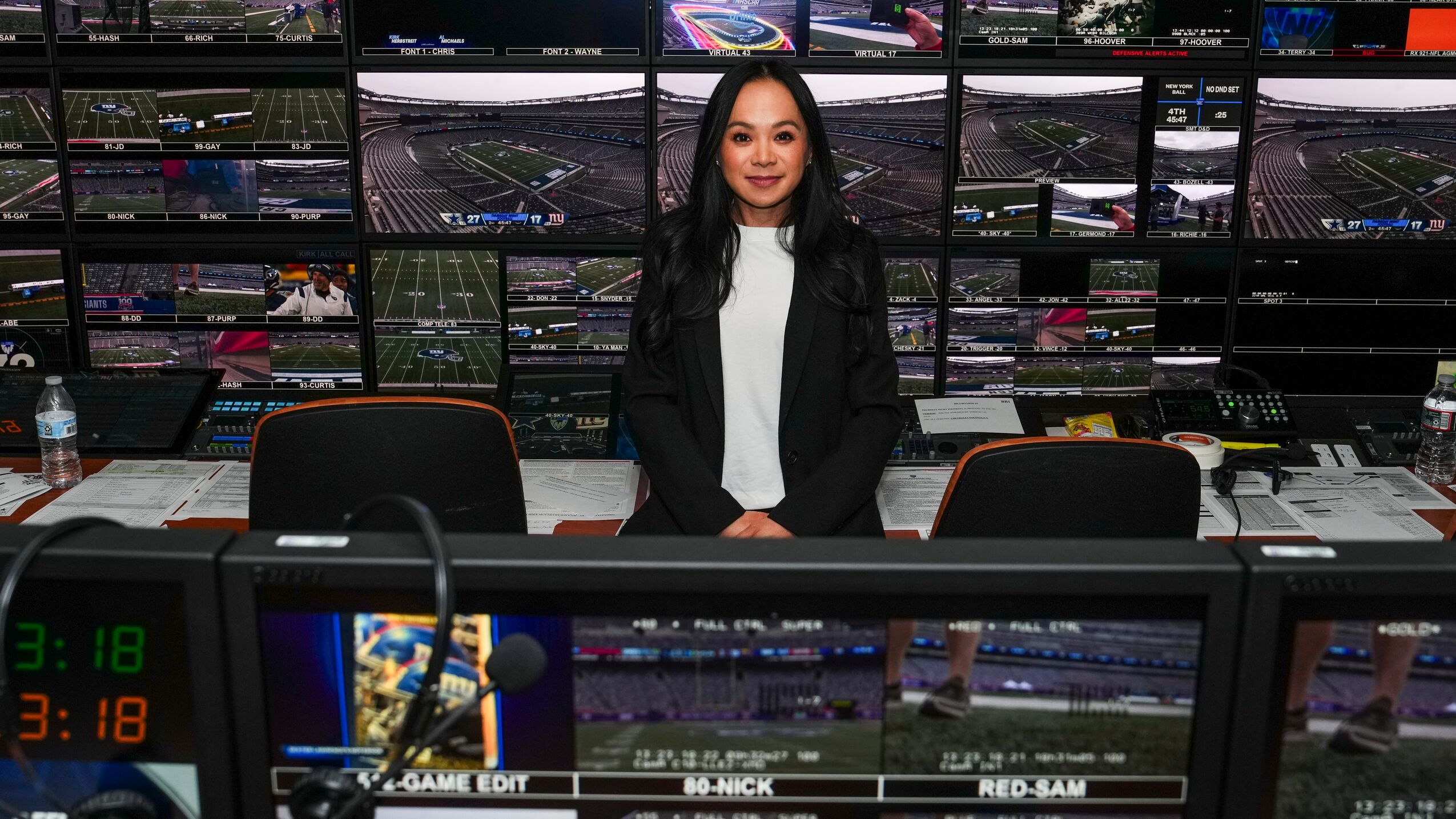 Woman stands in front of a bank of monitors during 'Thursday Night Football'