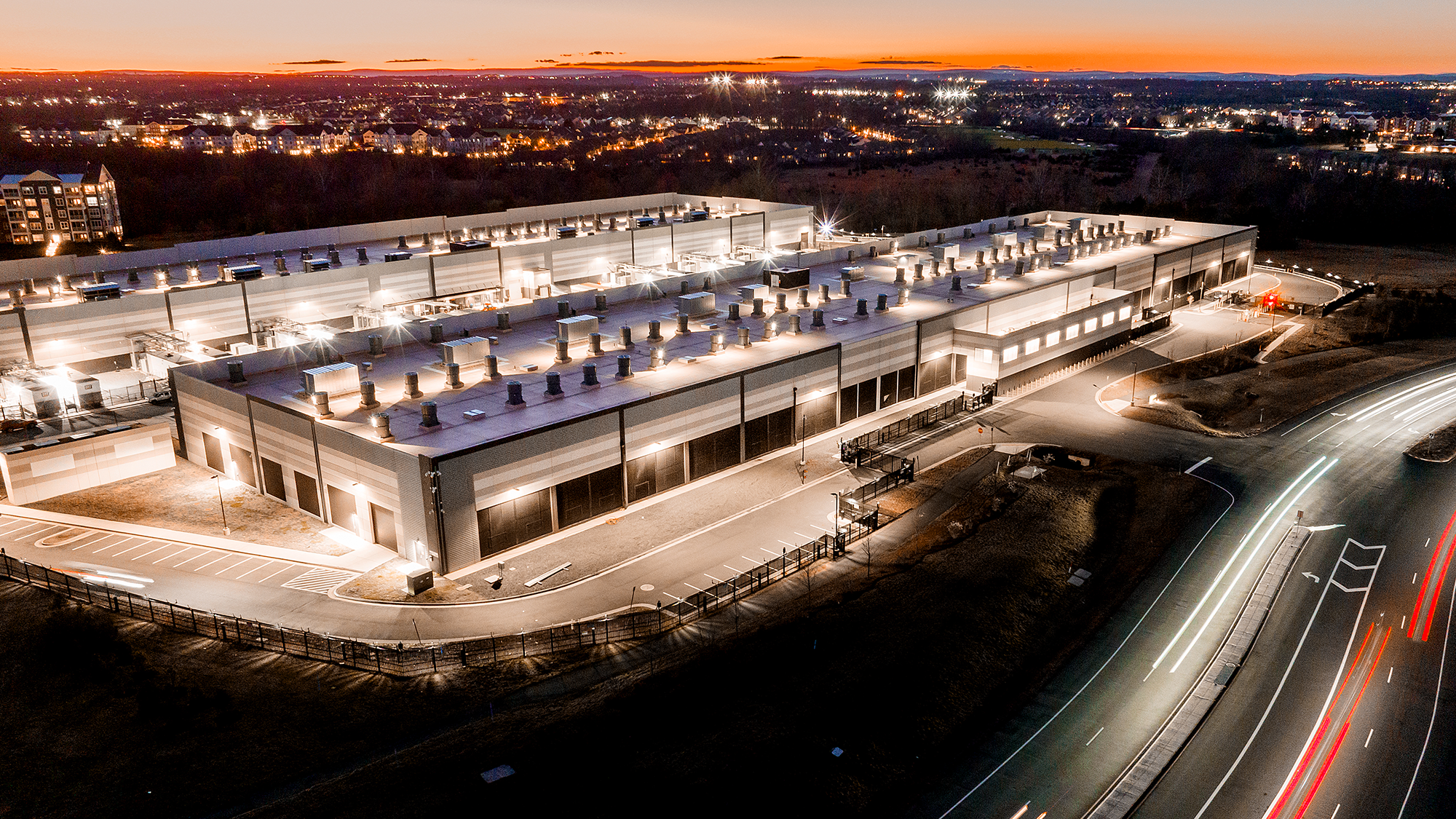 A photo of an AWS data center located in Virginia. The photo is an aerial shot from the night. 