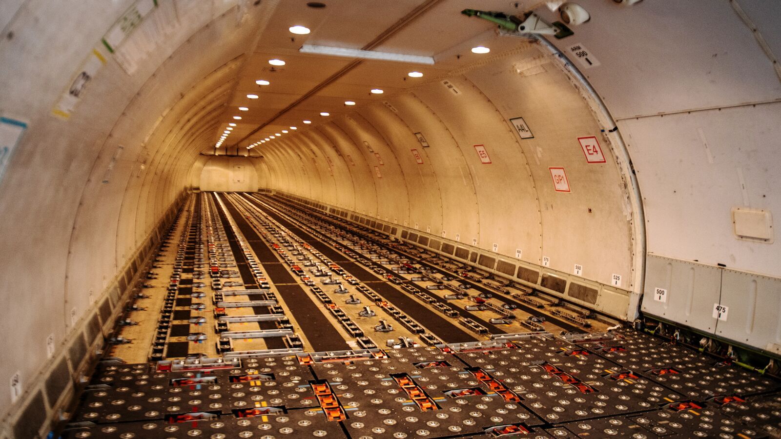 The inside of an Amazon Air plane. There are various metal lock systems, wheels, and bumps on the floor that help guide the containers inside.