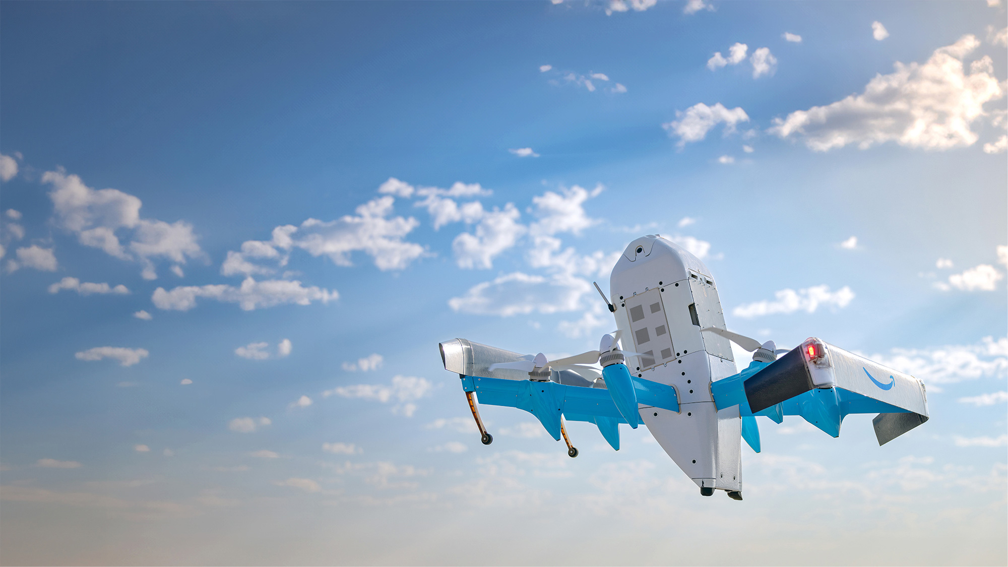 Amazon Prime Air drone flying in blue sky with scattered clouds