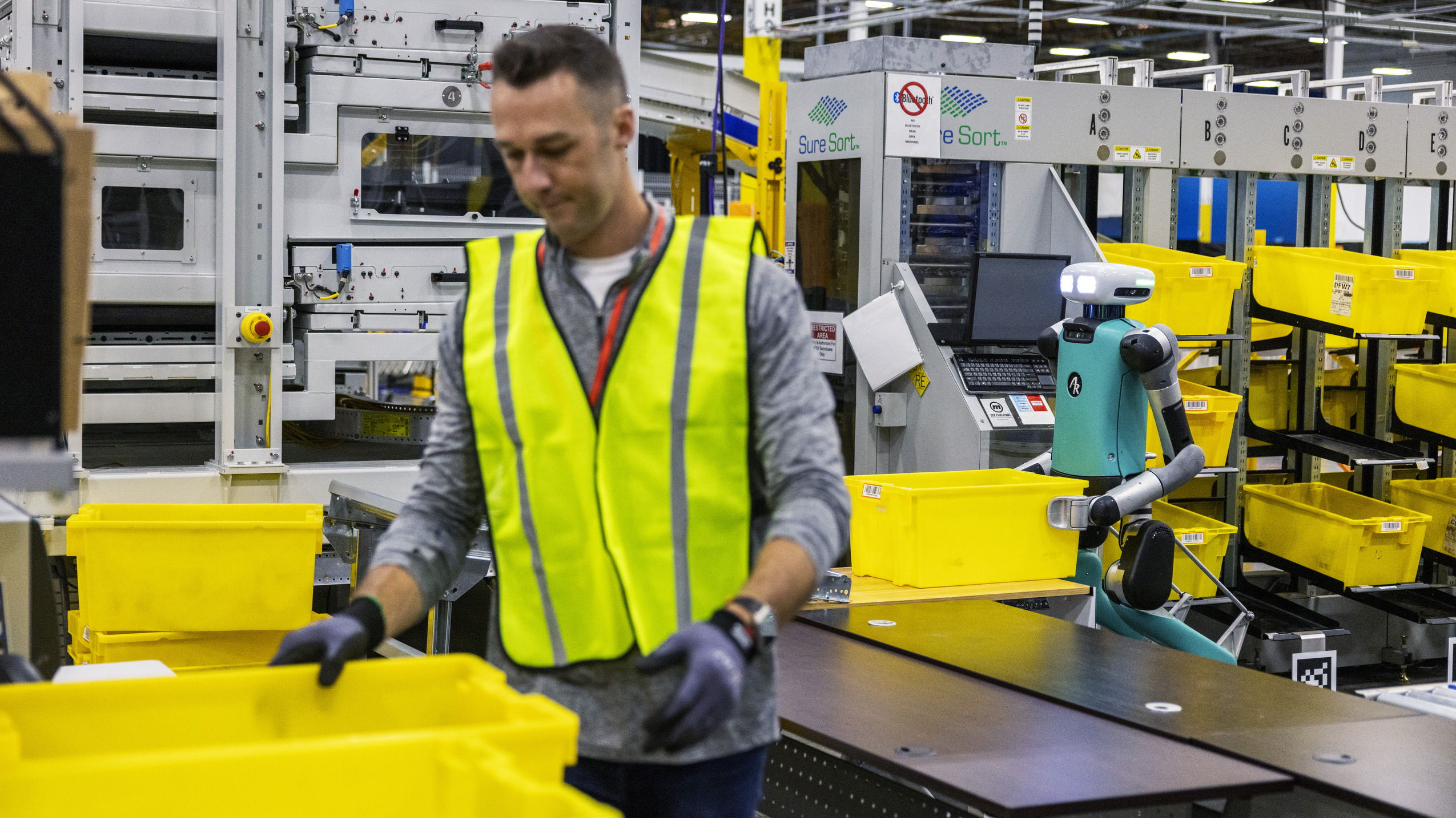 An image of the bi-pedal robot, Digit, working alongside an Amazon employee