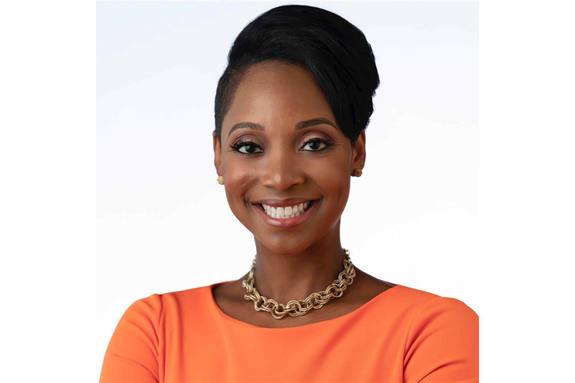 A woman smiles at the camera, her arms crossed in front of her. 