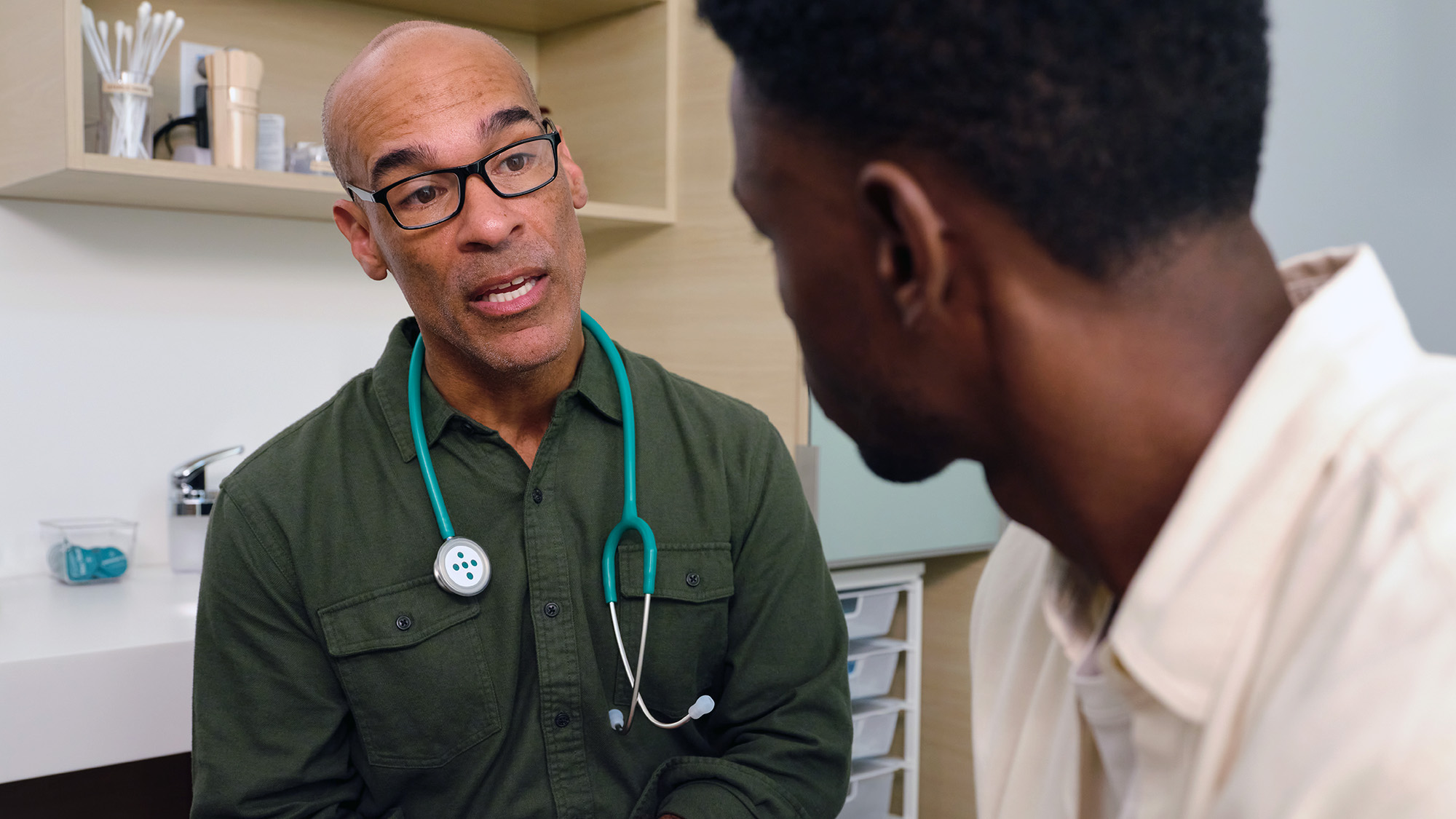 A doctor speaking to a patient in an exam room. 