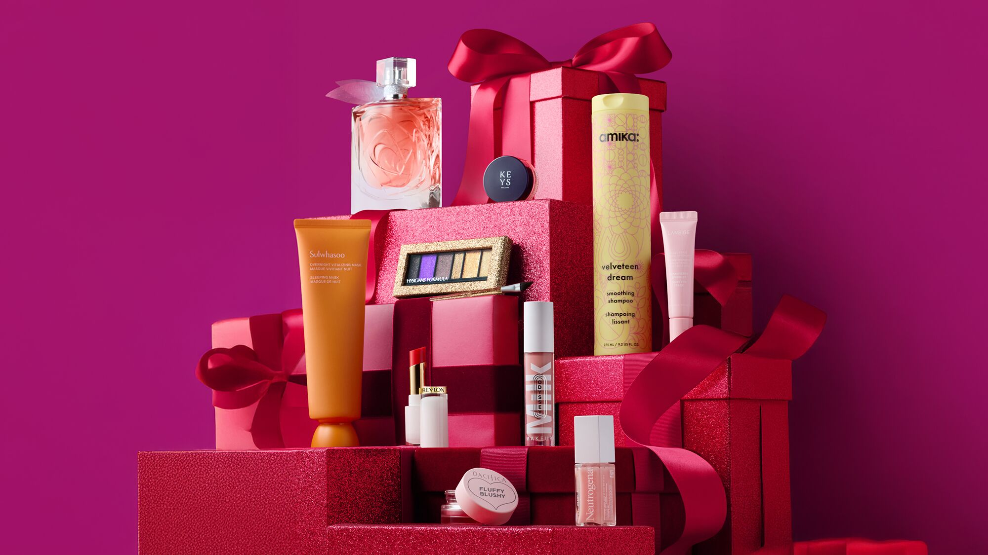 Beauty products arranged on red gift boxes against pink background