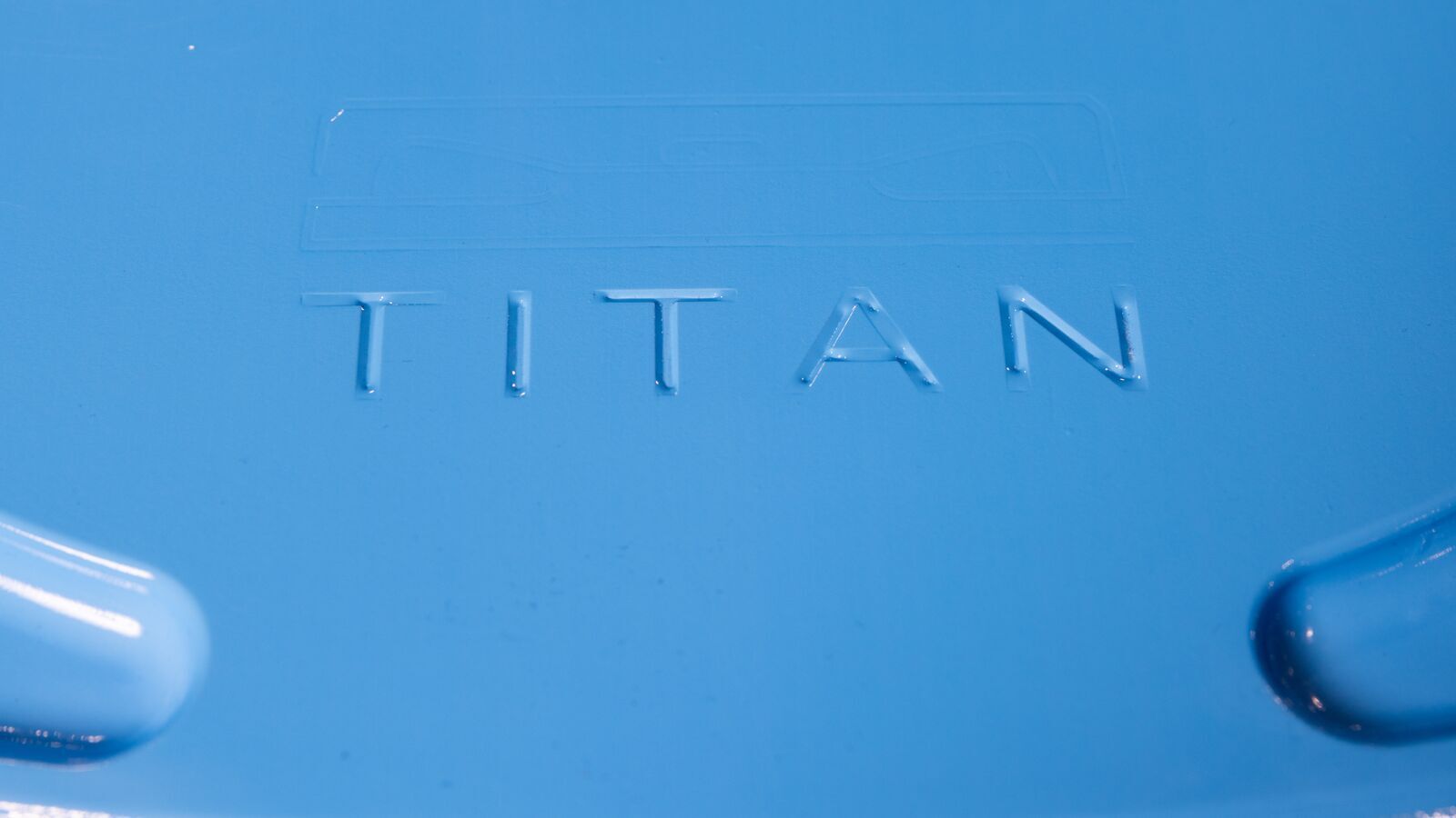 A close-up image of the logo on the new Amazon fulfillment center robot, Titan. The surface is a light-blue metal and the name "Titan" is imprinted in the center.