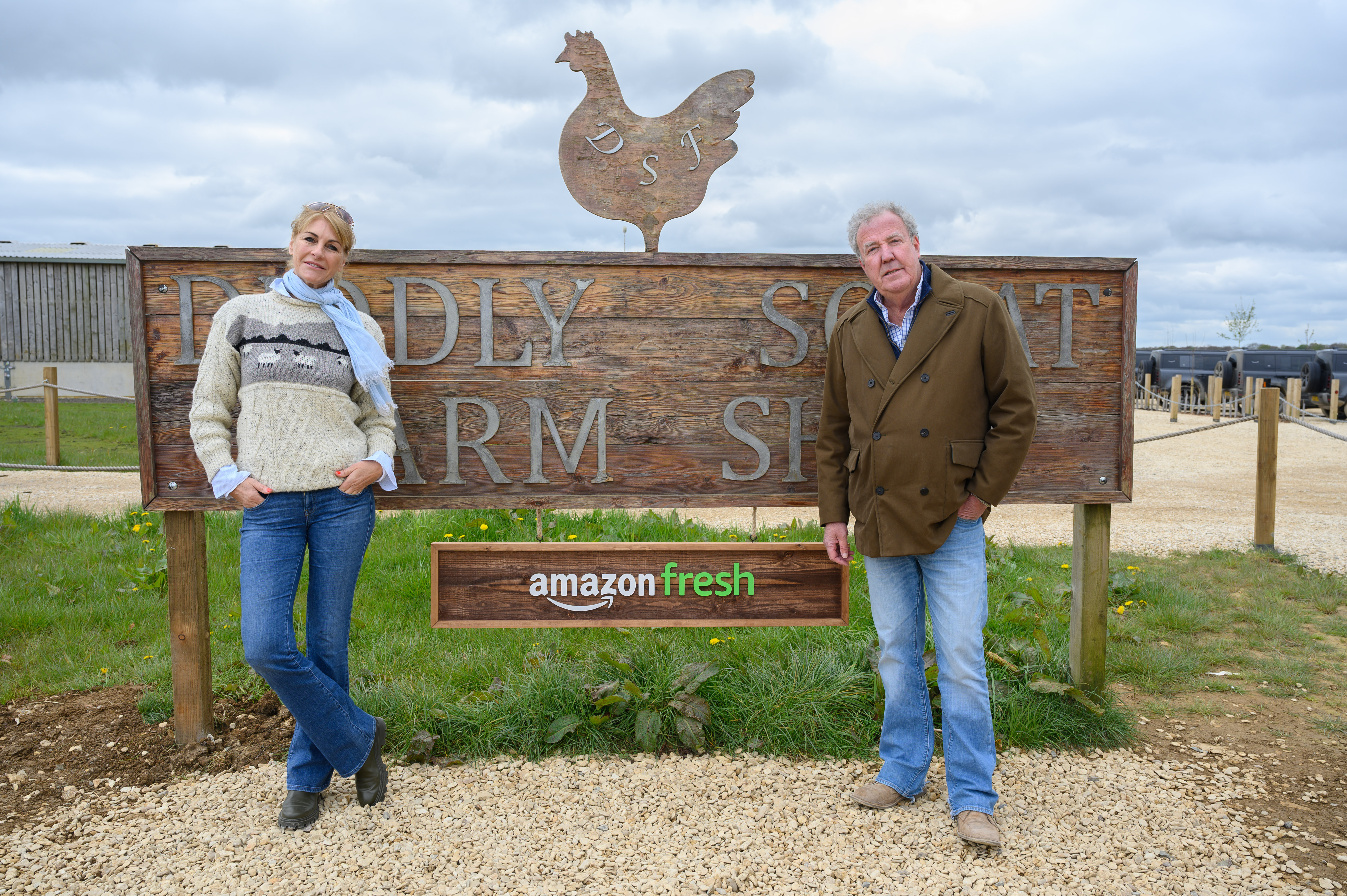 A man and a woman standing in front of a sign on a farm