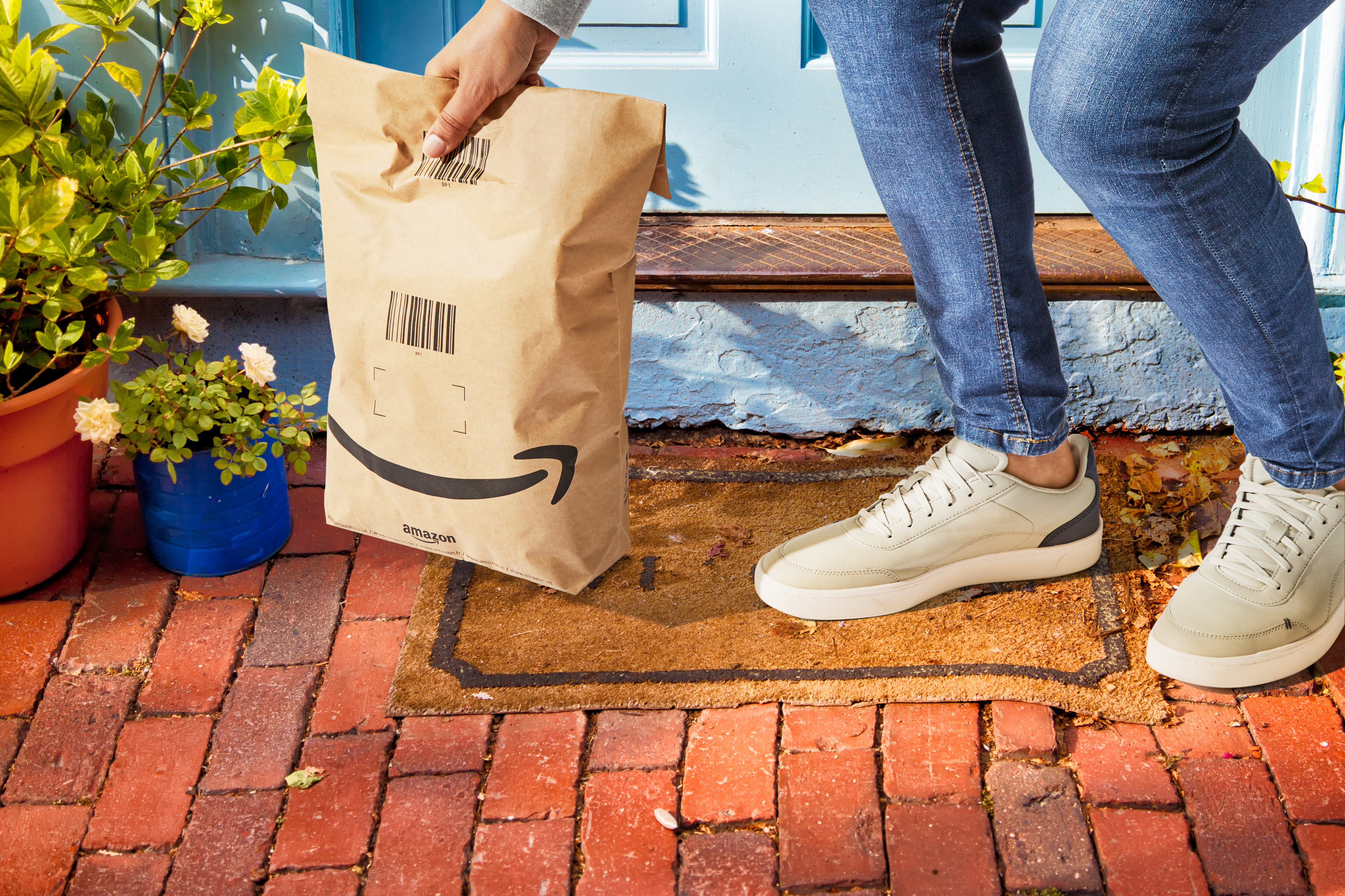 A customer picking up an Amazon delivery in a paper bag with less packaging