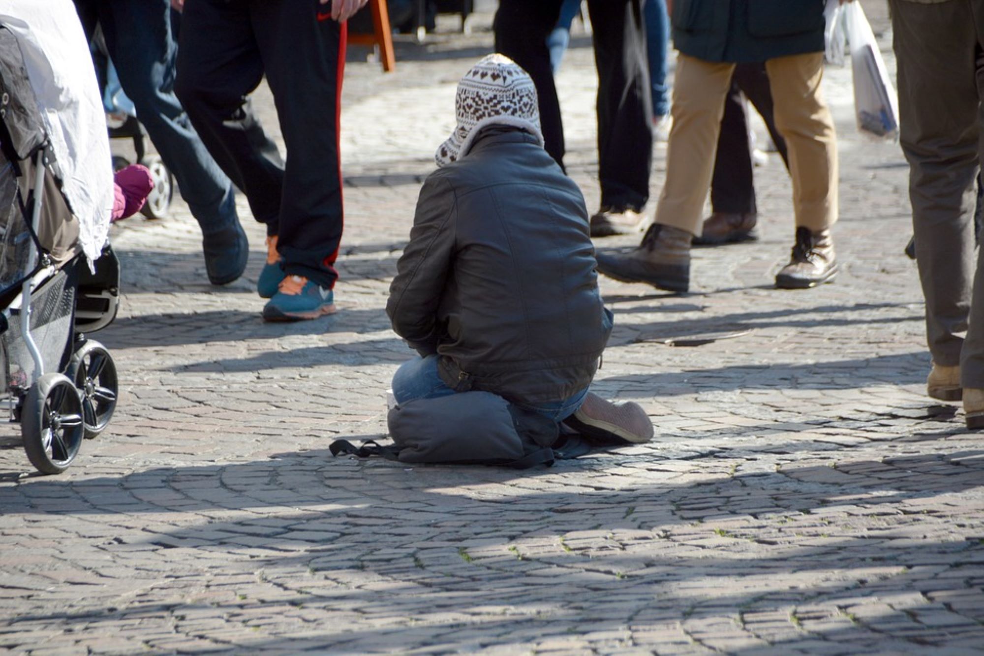 obdachloses kind sitzt auf der Straße, Menschen laufen drumherum