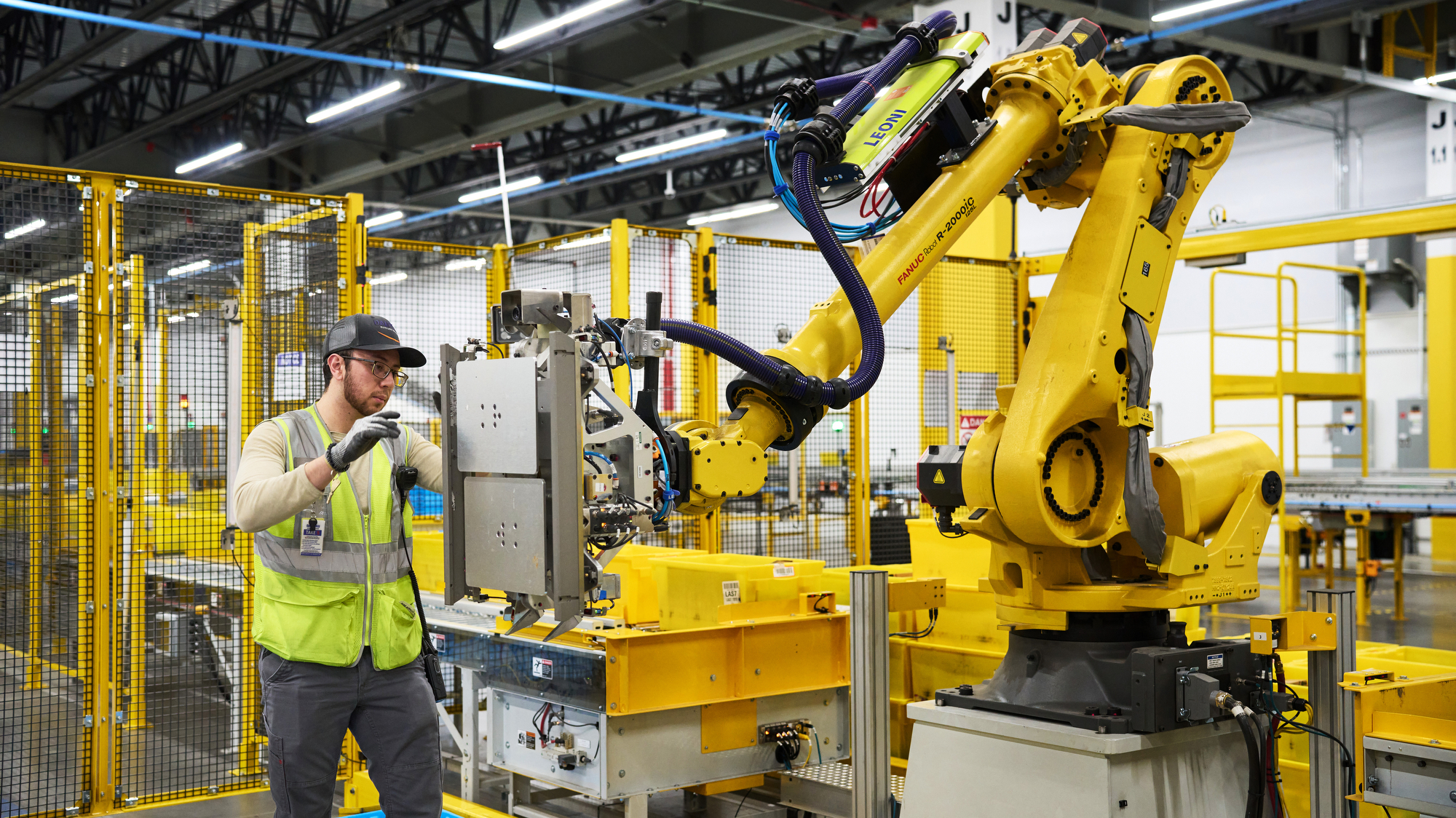 An image of an employee working with a robotic system in an Amazon fulfillment center