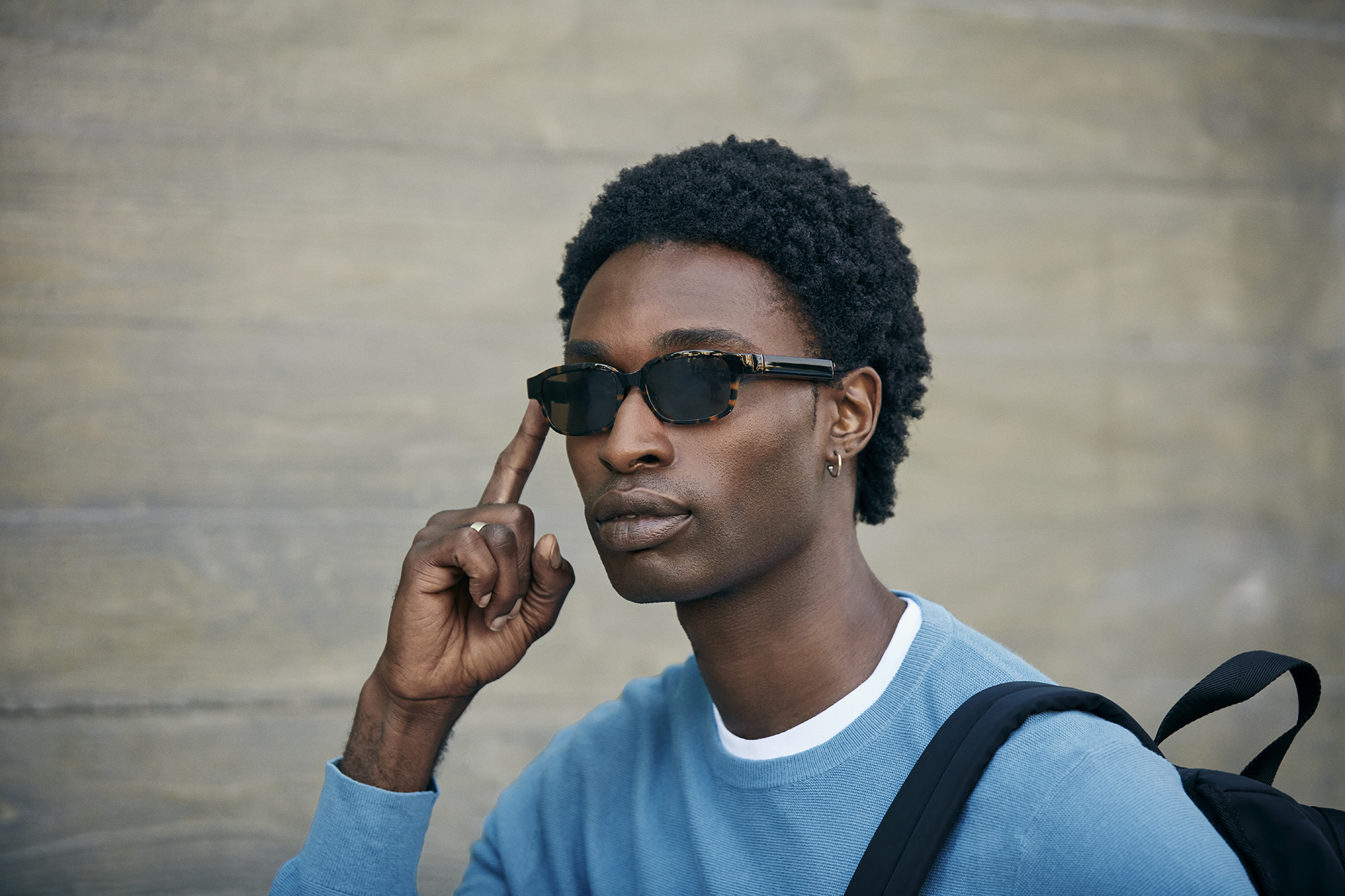 A man wears modern tortoise Echo Frames and activates Alexa with the touch of his finger.