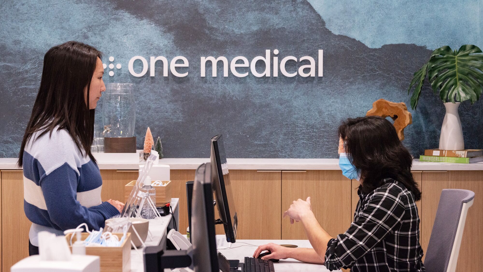 senior writer connie chen talking to the receptionist in front of a sign that says one medical, inside the nomad one medical office in new york city