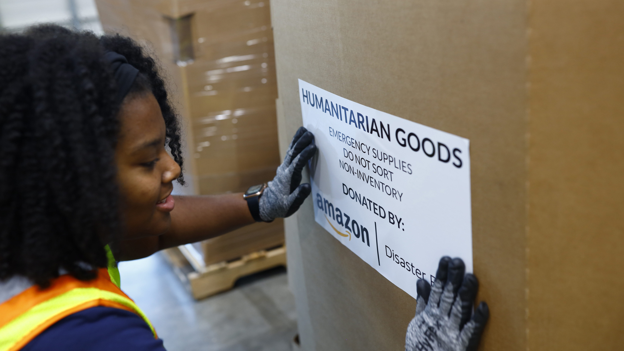 An Amazon employee places a sticker that reads "Humanitarian goods" on a big box filled with relief items.