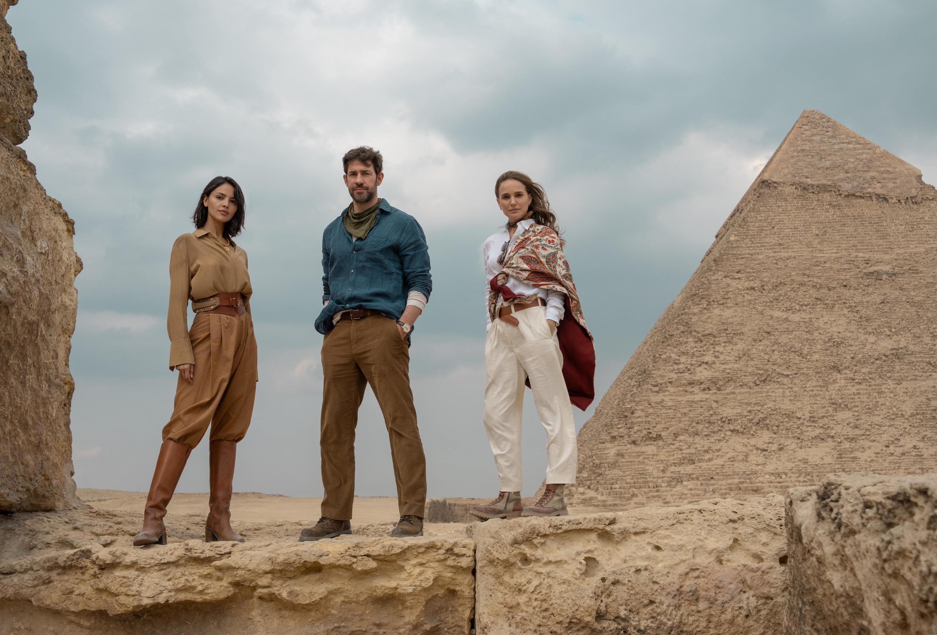 A group of adventurers standing on desert rocks near ancient Egyptian pyramid in the Fountain of Youth on Prime Video