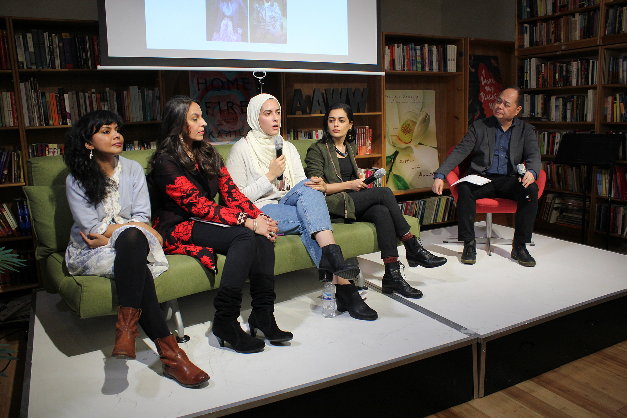 Five AAWW members, shown seated, four women sit side-by-side on a green sofa, a male sits to the right. 