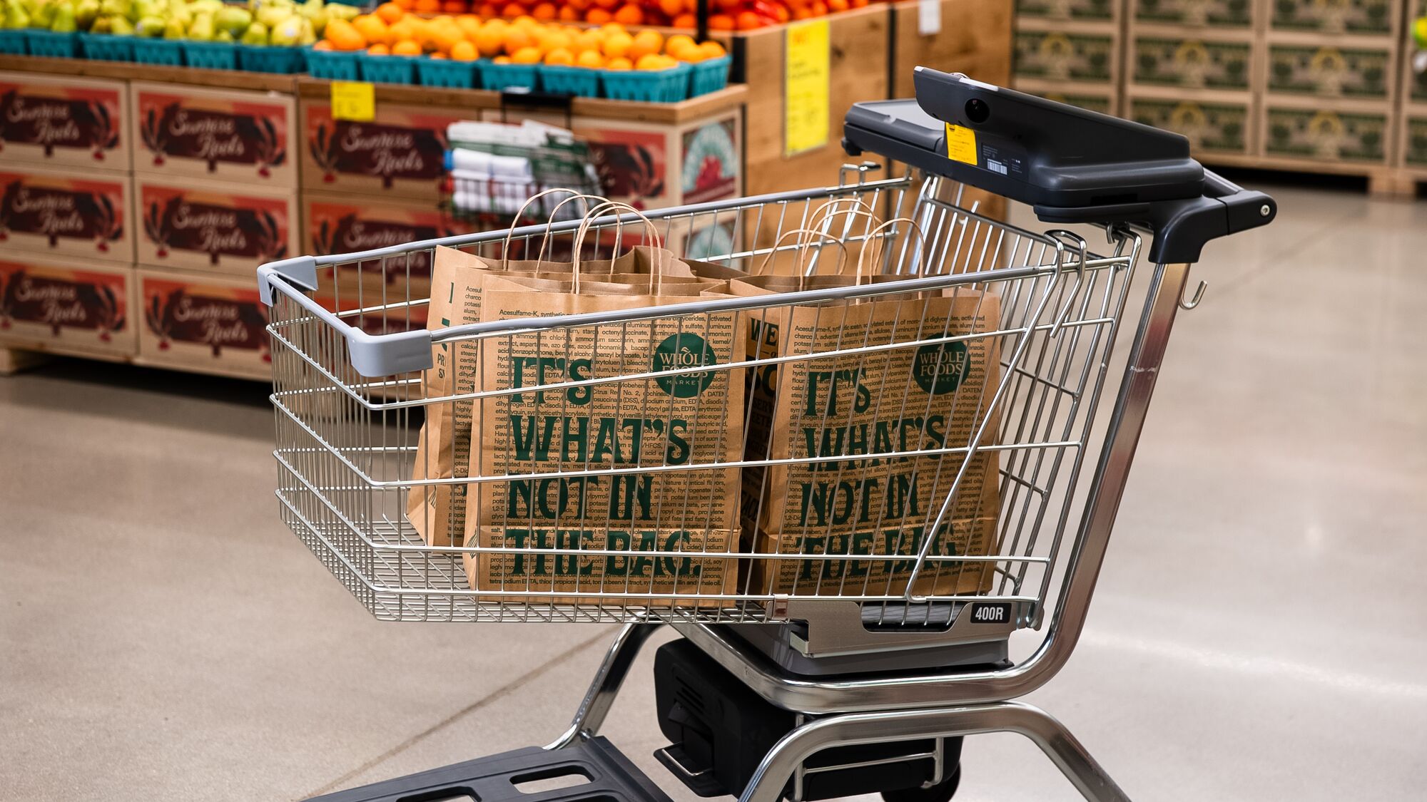 Shopping cart with Whole Foods bags in grocery store produce section
