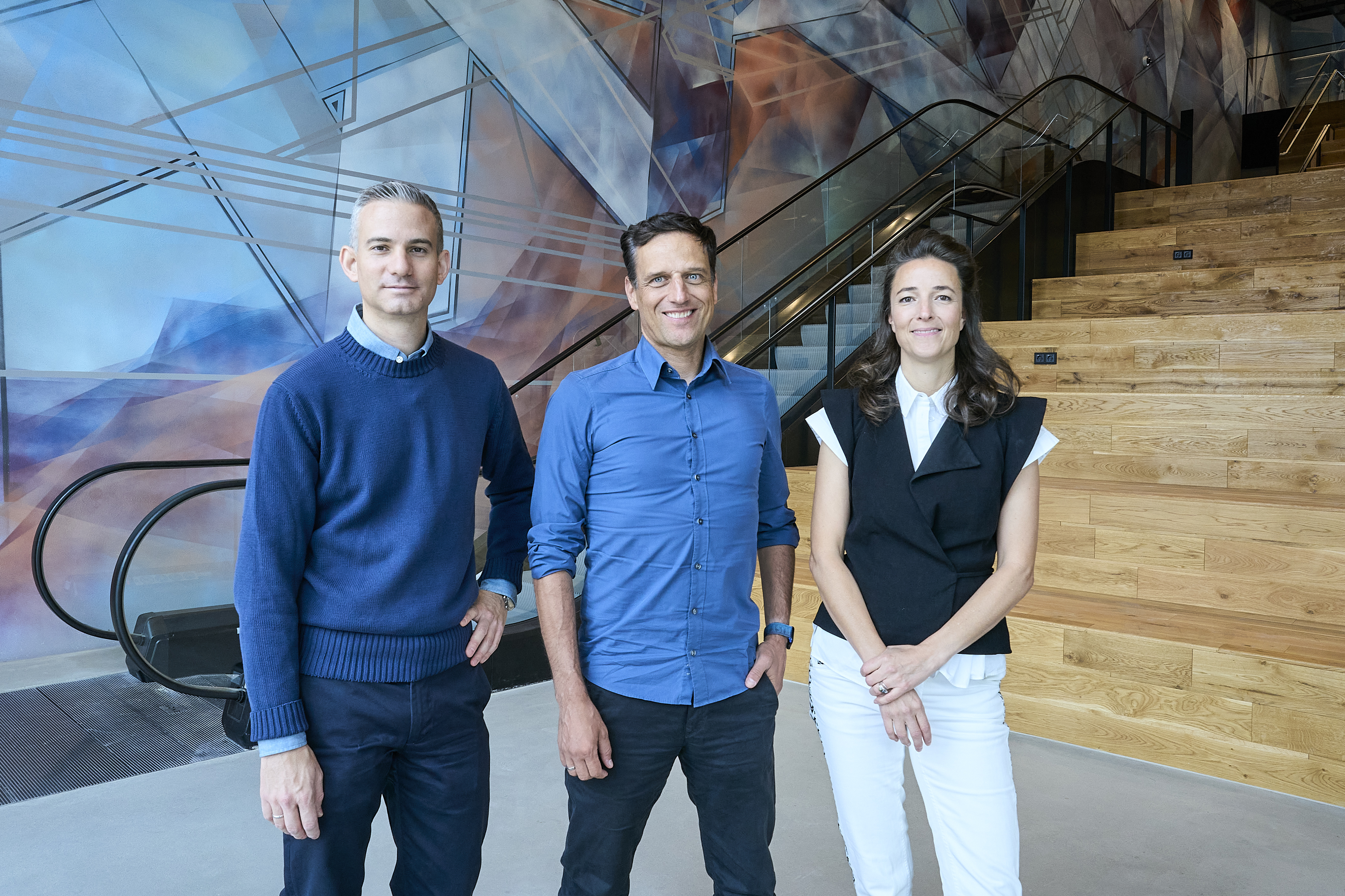 Jonathan Weiß, Leiter des Forschungs- und Entwicklungsstandorts von Amazon in Berlin, Rocco Bräuniger, Country Manager von Amazon in DACH, und die Künstlerin Alina Mann vor dem 180m2 großen Wandgemälde "Unfold" im EDGE East Side Berlin.