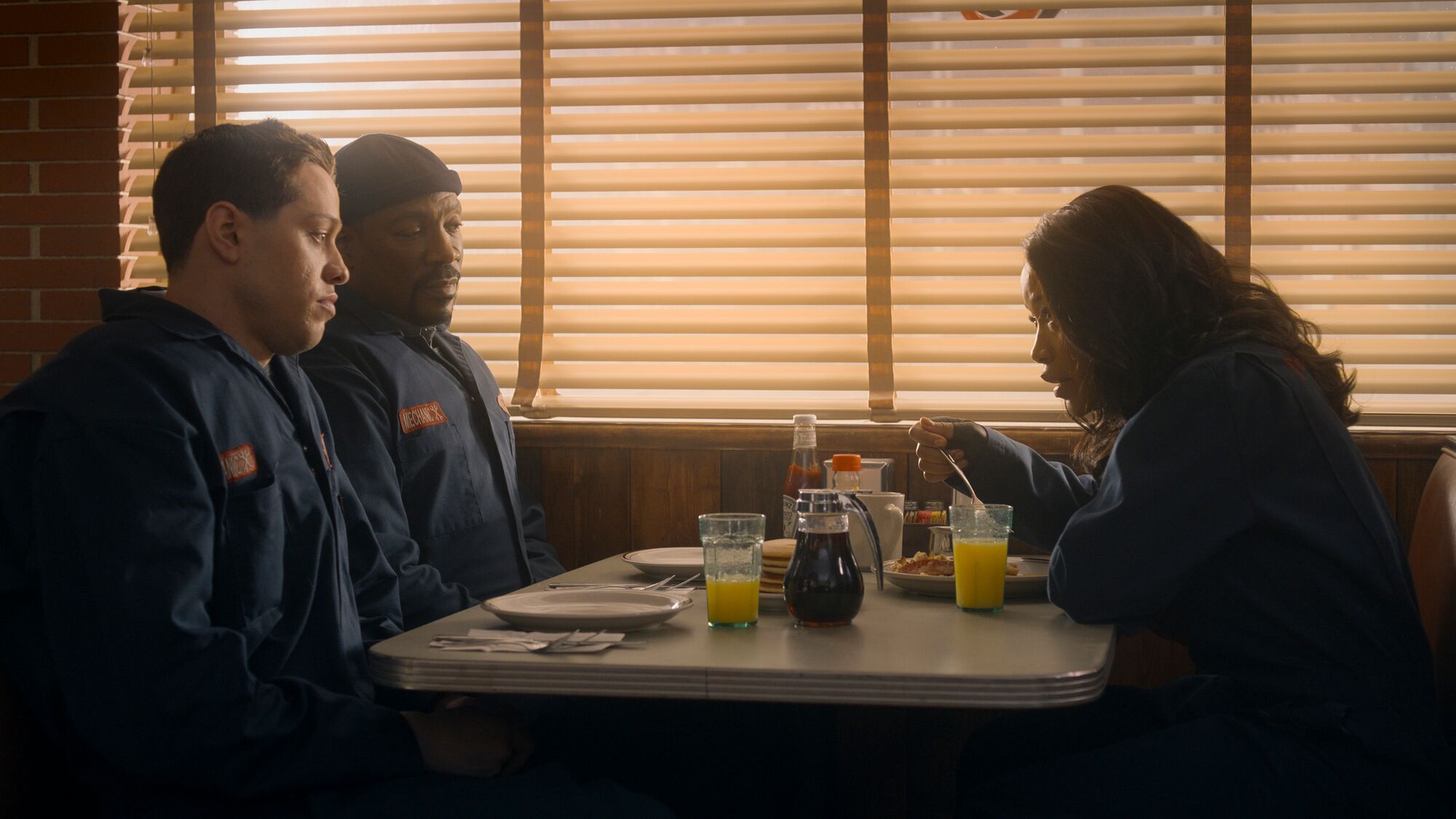 Two men and a woman talk at a diner