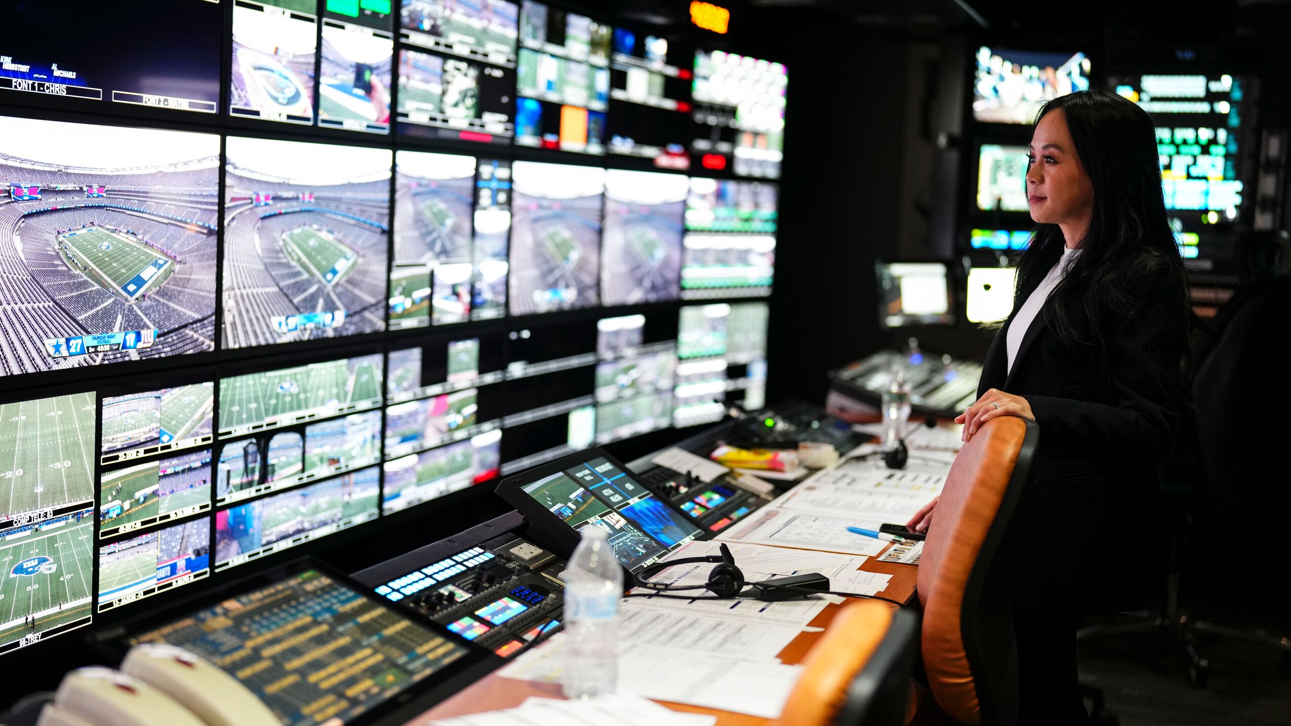 Woman looks at a gallery of monitors during Thursday Night Football