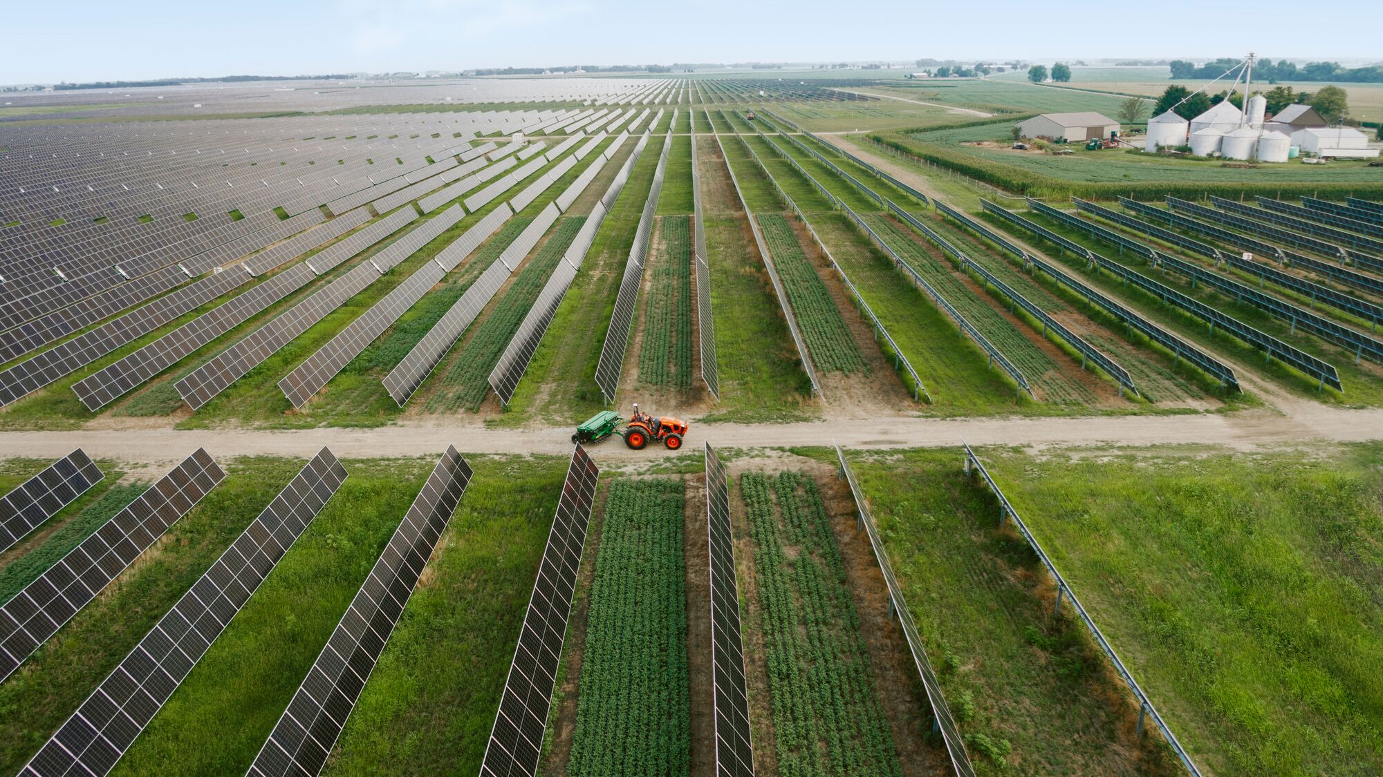 carbon-free energy at Amazon, a photo of a solar farm with rows of panels alongside agricultural fields and a tractor