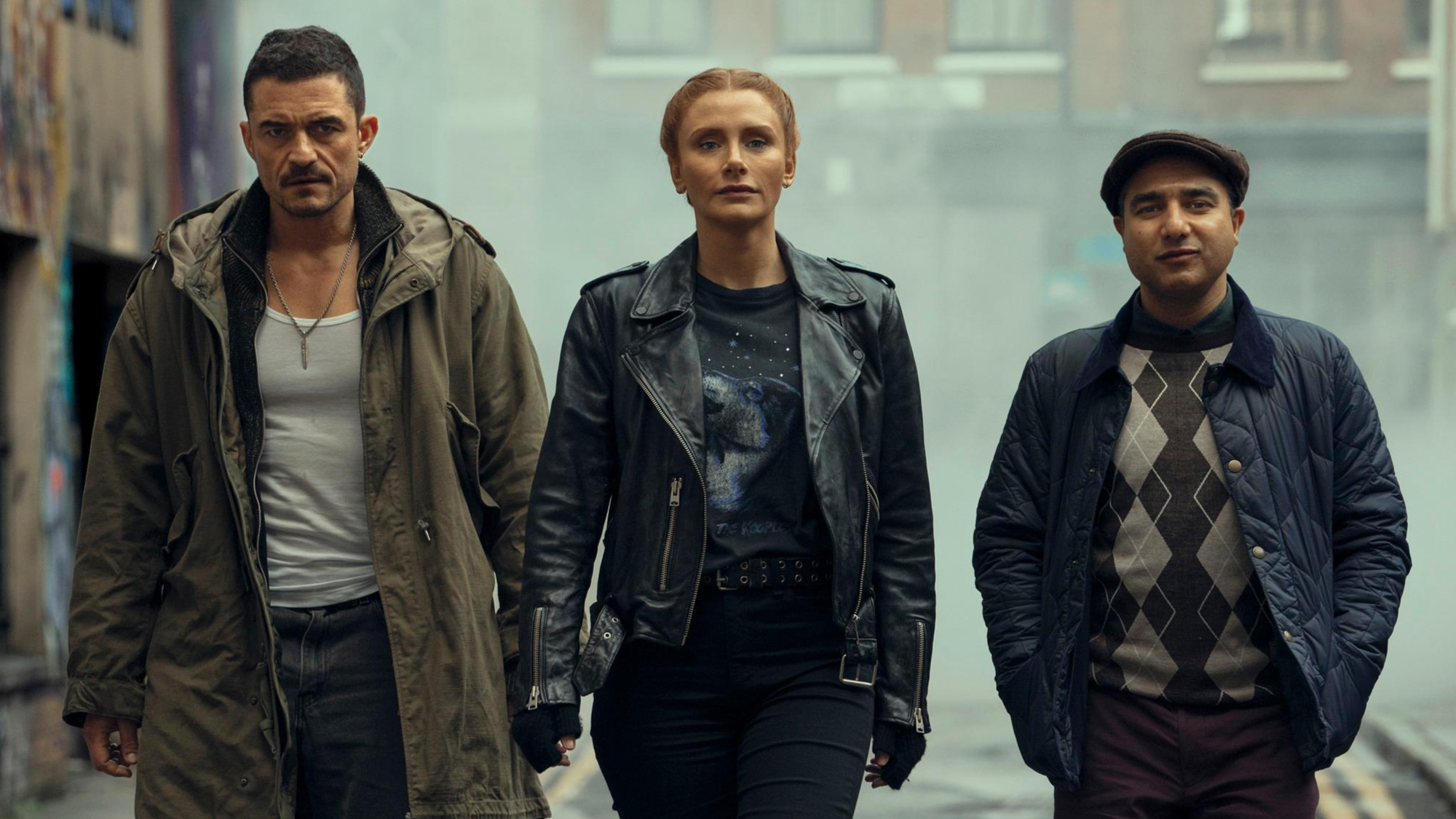 Three diverse individuals in urban streetwear walking confidently down an alley