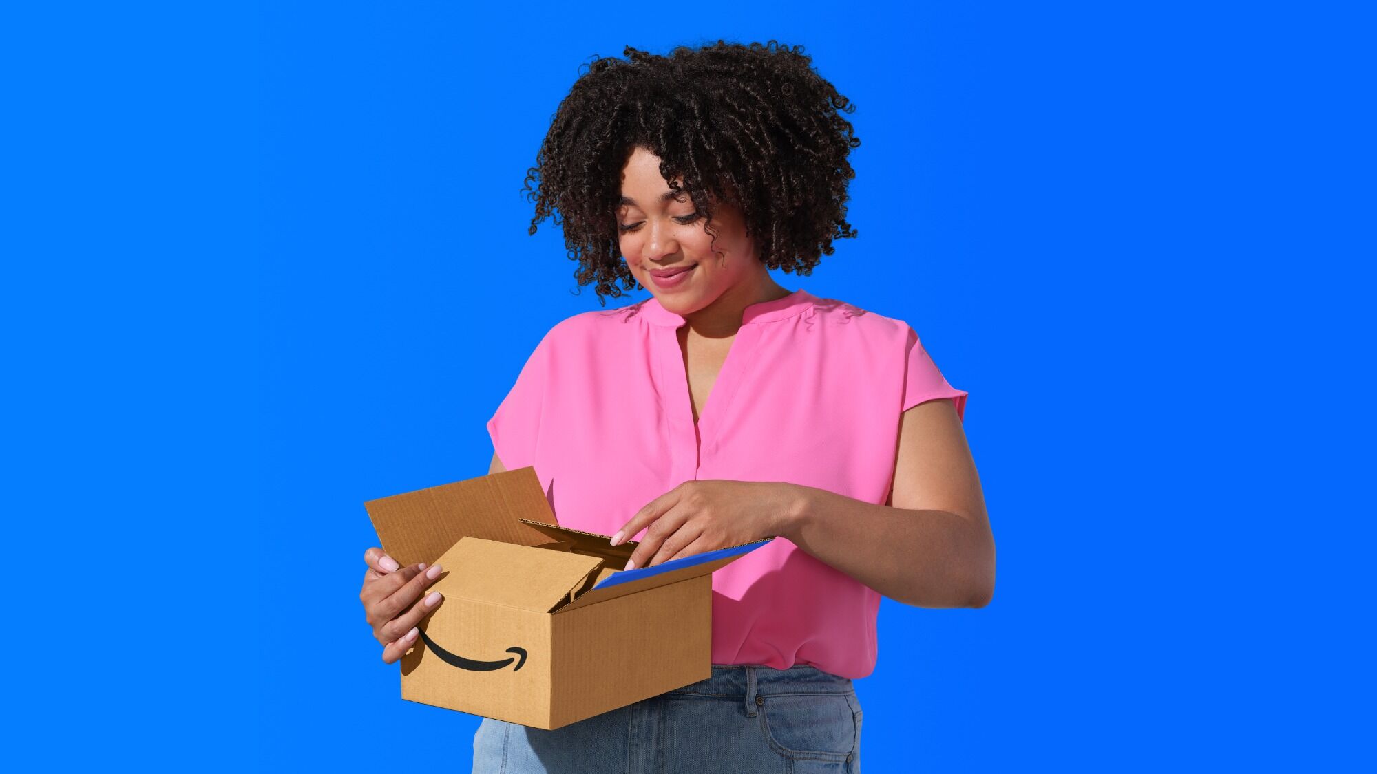 Woman smiling while opening an Amazon delivery box