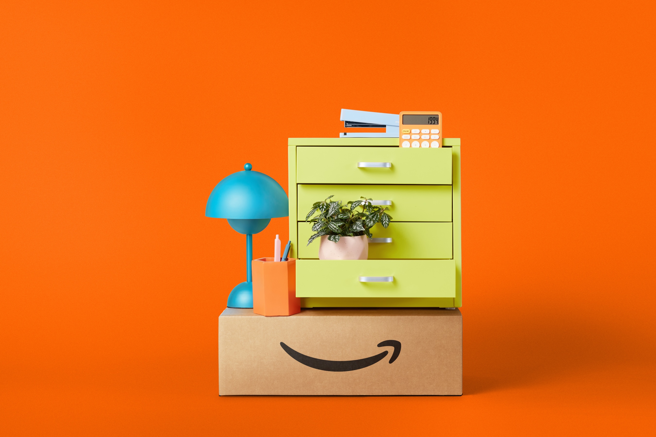 Amazon products stacked ontop of a delivery box, including a lamp and a filing cabinet