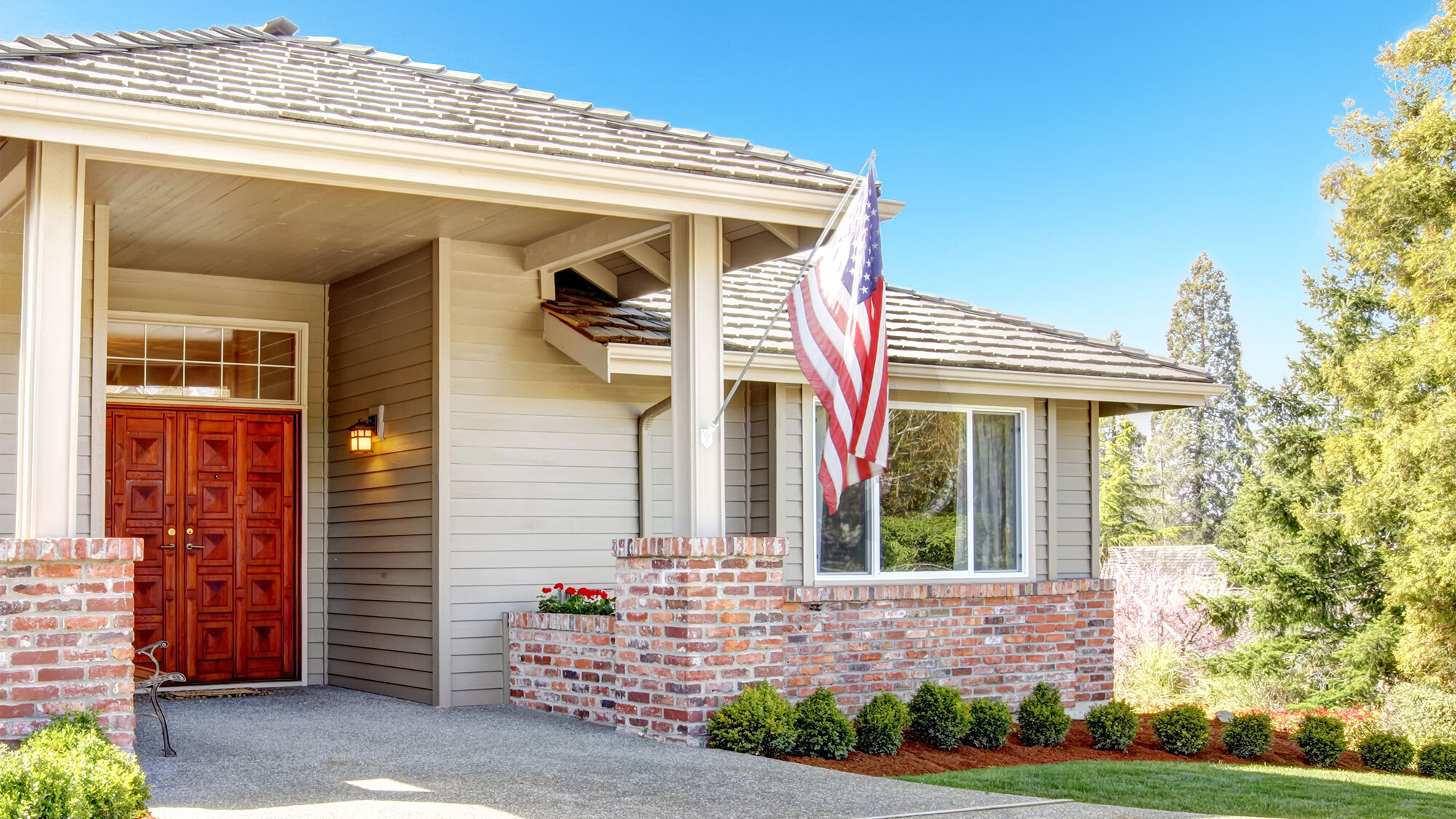 A home in the summertime with an American flag hanging from it.