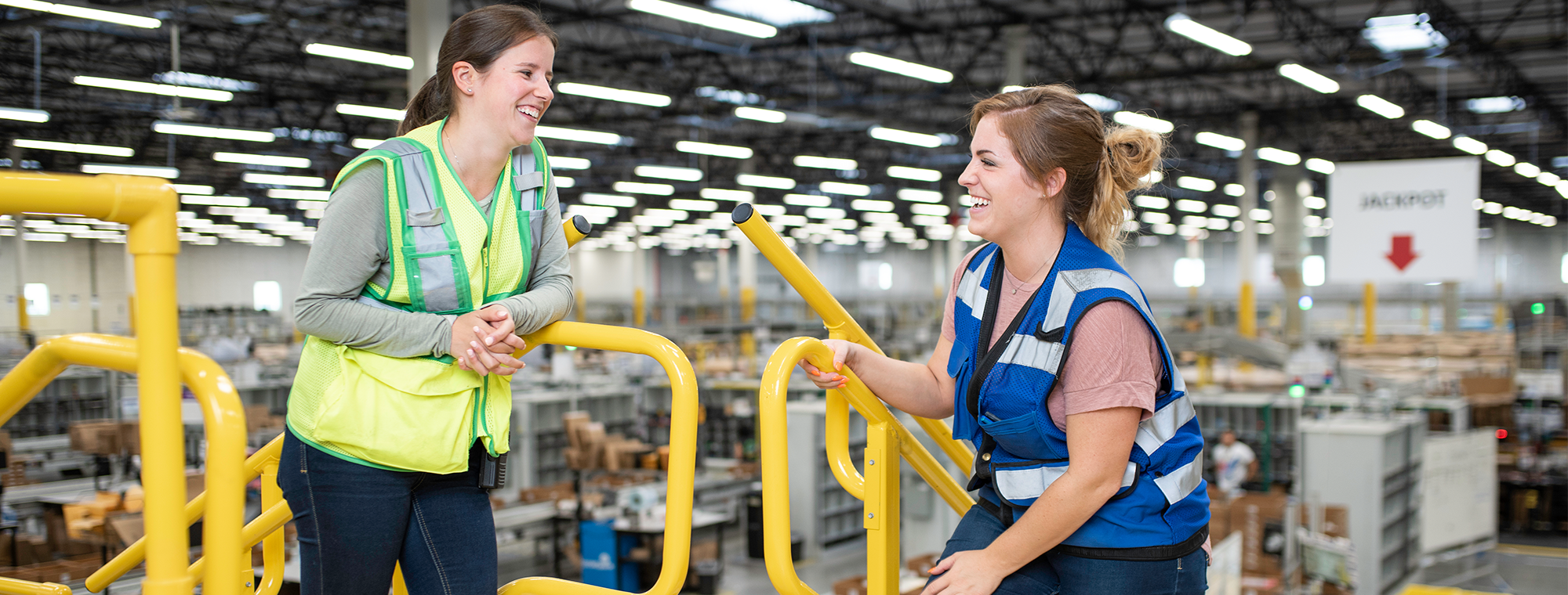 Zwei Frauen mit Sicherheitswesten in einem Amazon Logistikzentrum