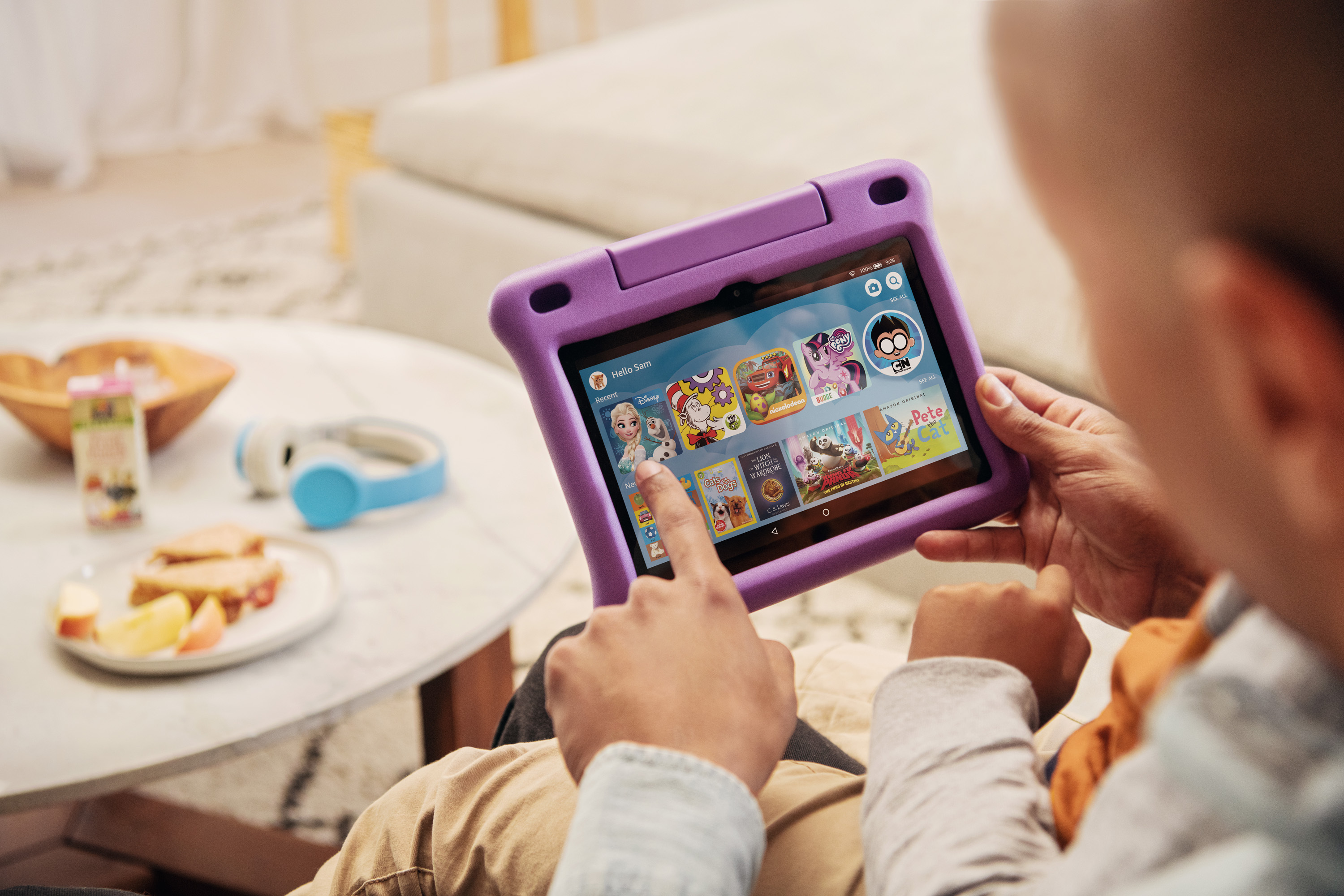 A father and child play with a Fire HD8 kids edition tablet together, in the foreground a snack awaits.