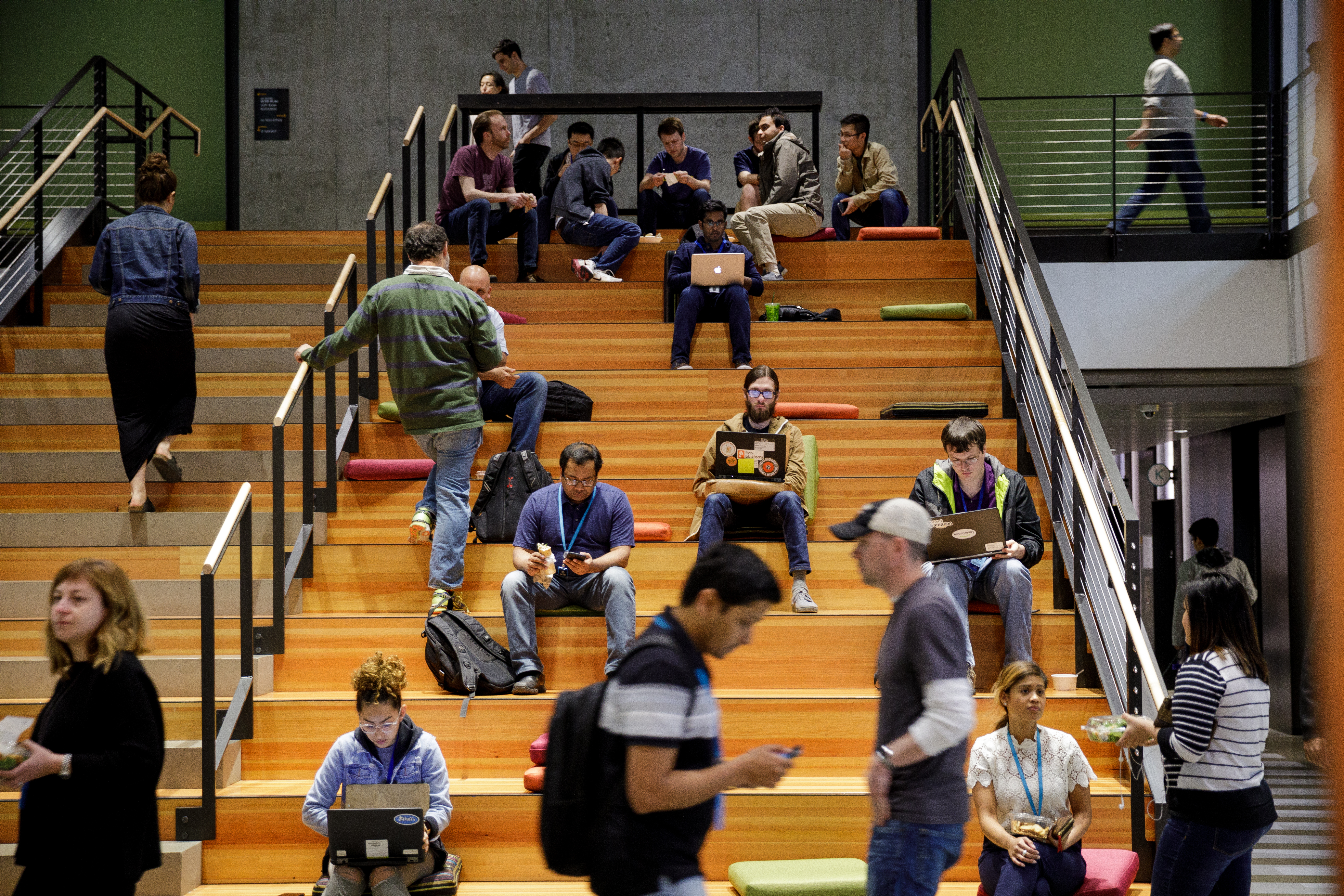 A stairwell in Amazon's Seattle Headquarters is used by employees for sitting, standing, walking, and working.