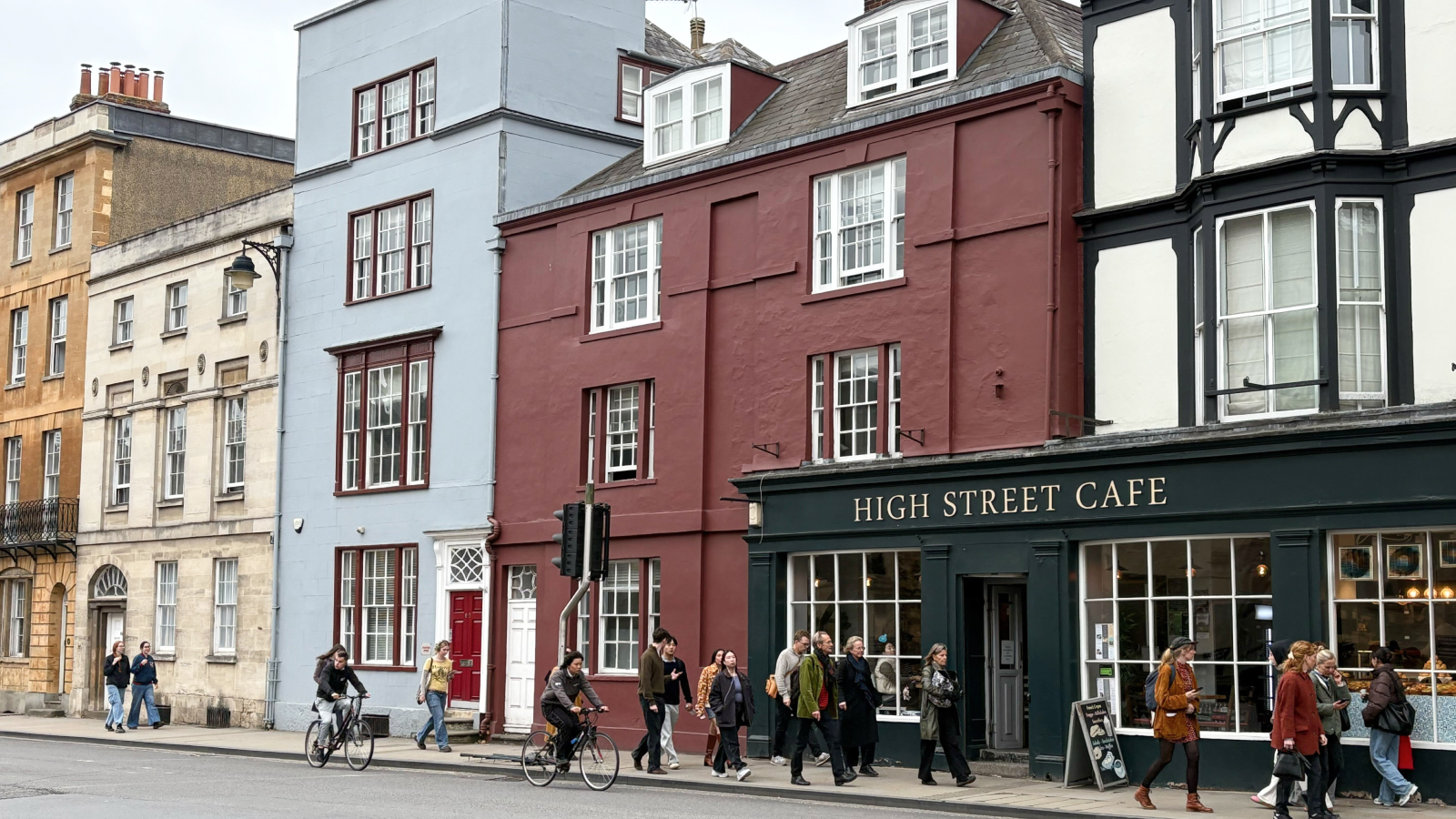 Farbenfrohe historische Gebäude an der belebten High Street mit Cafés und Fußgängern