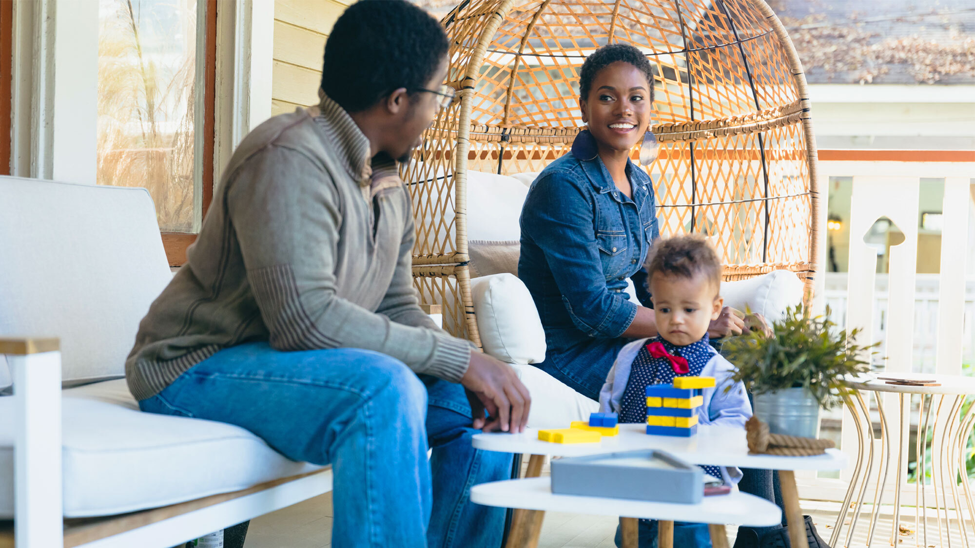 A photo of a couple sitting on a porch with their baby.