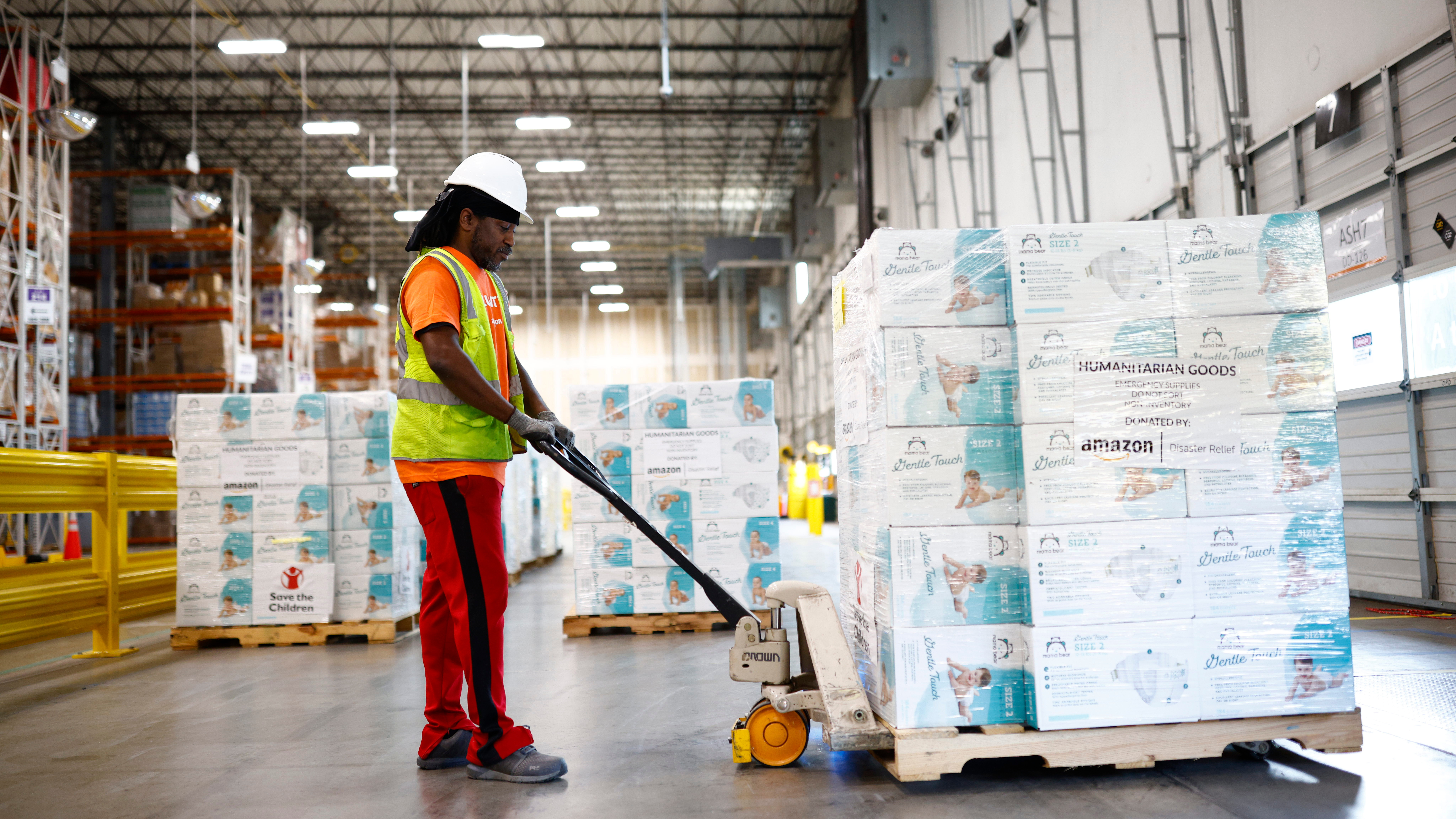 Warehouse worker moving pallet of humanitarian goods donated by Amazon