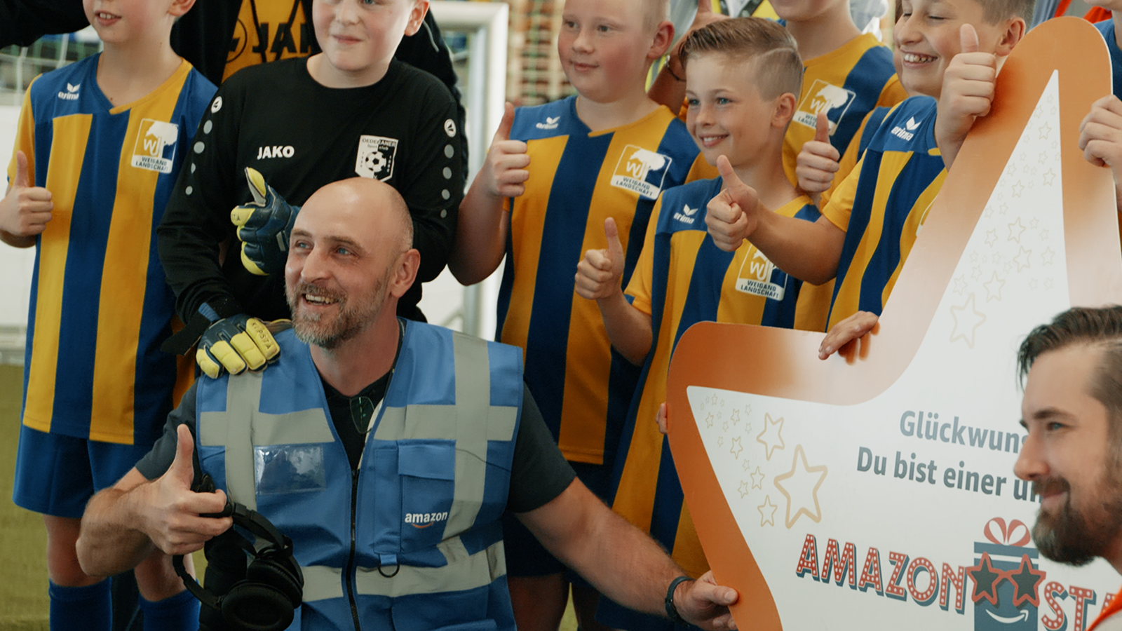 Amazon Star Enrico mit den Fußballkids, die er trainiert, im Sortierzentrum.