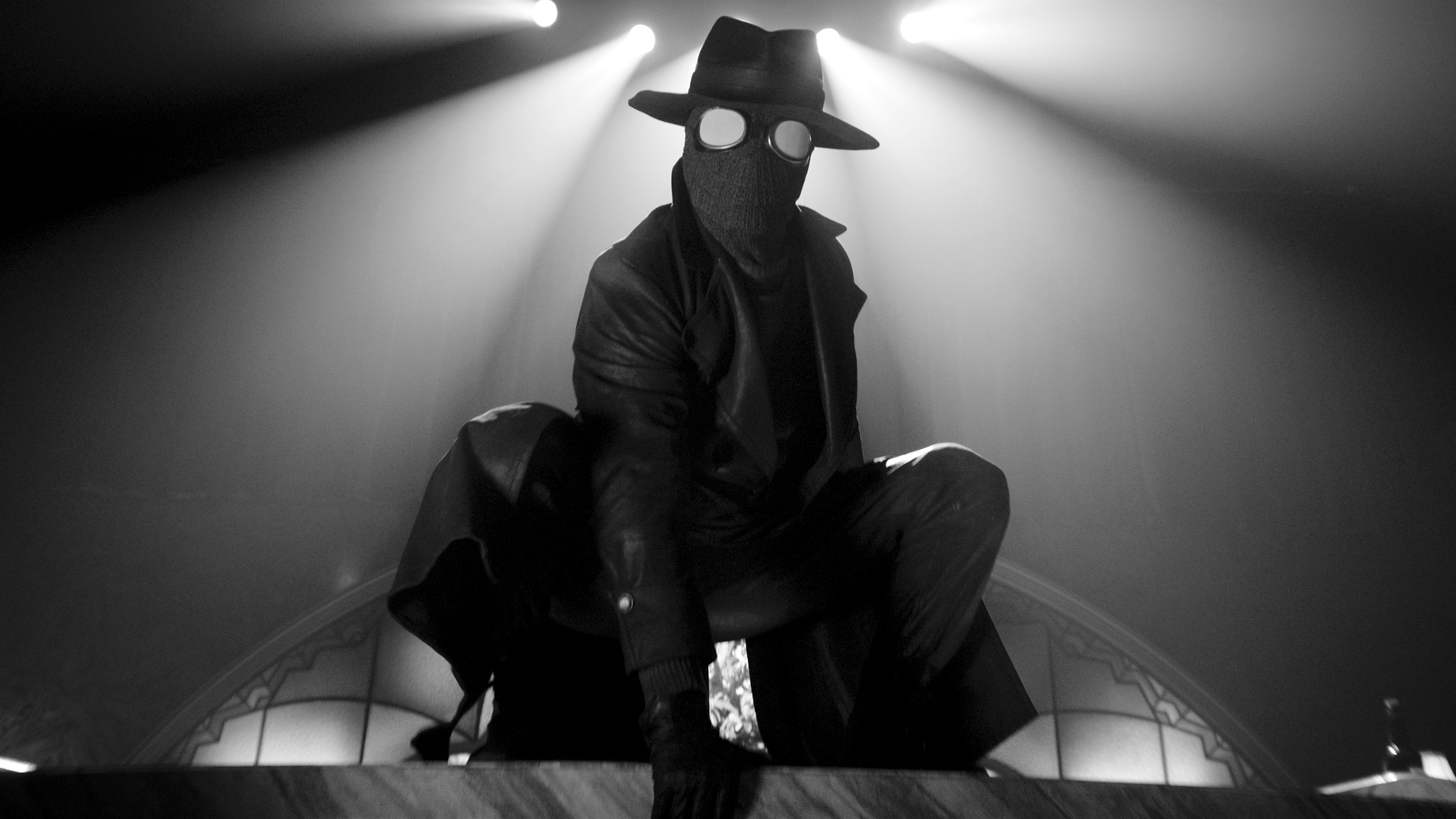 Mysterious figure in hat and mask illuminated by dramatic spotlights
