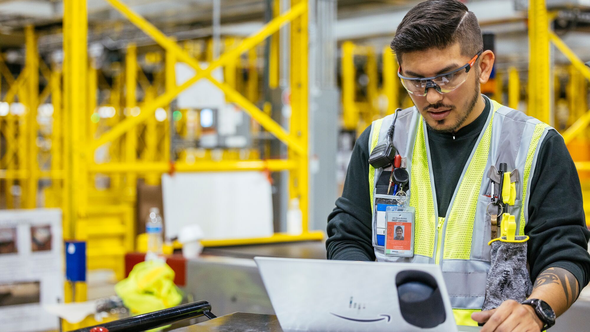 An image of a robotics technician working on a laptop in an Amazon fulfillment center.