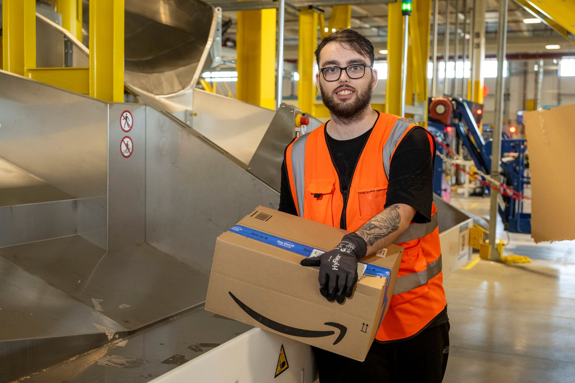 Amazon employee Colby Baker in orange safety vest holding Amazon package
