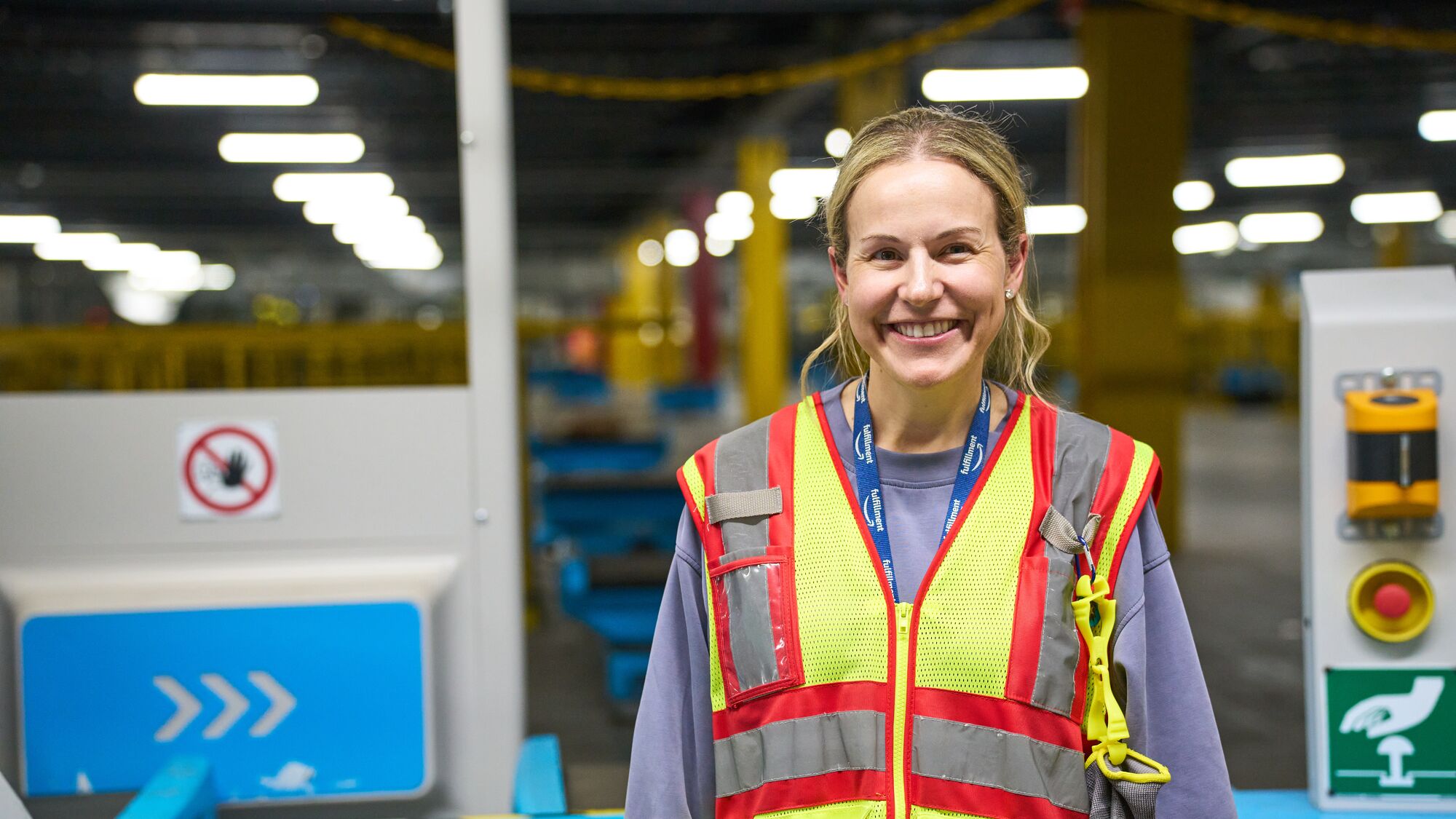 Smiling warehouse worker in safety vest and lanyard
